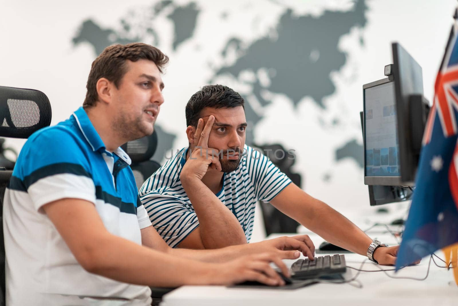 Group of Casual businessmen working on a desktop computer in modern open plan startup office interior. Selective focus. High-quality photo