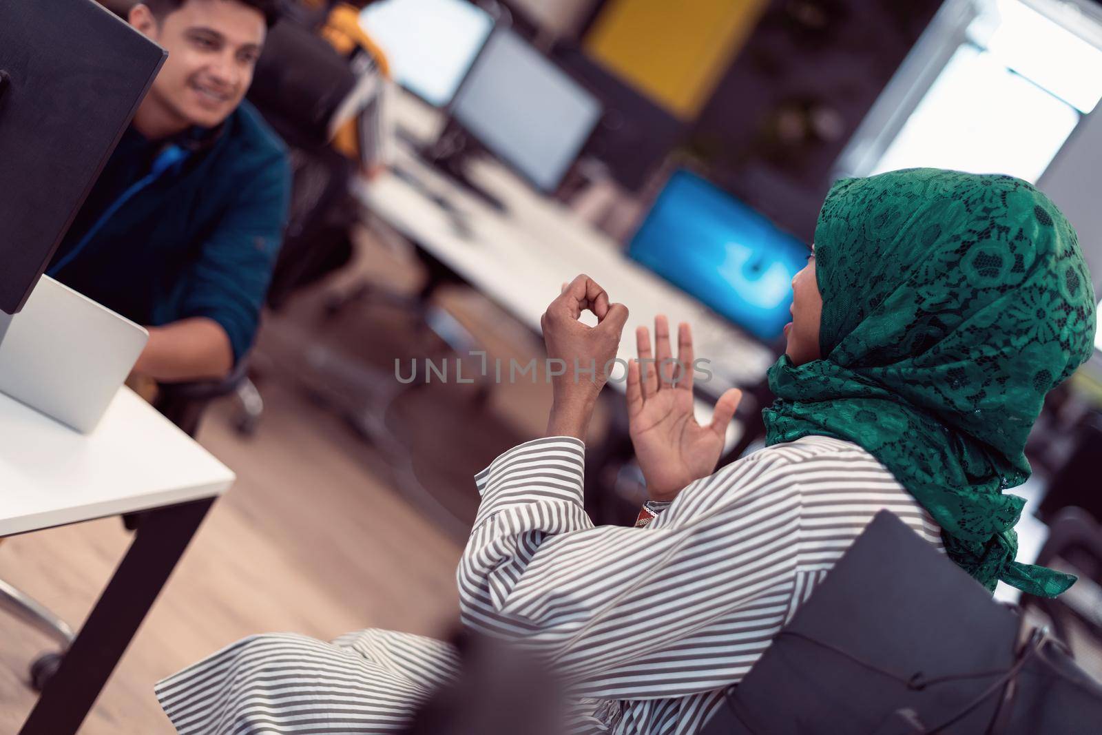 Multiethnic startup business team Arabian woman wearing a hijab on meeting in modern open plan office interior brainstorming, working on laptop and desktop computer. Selective focus. High-quality photo