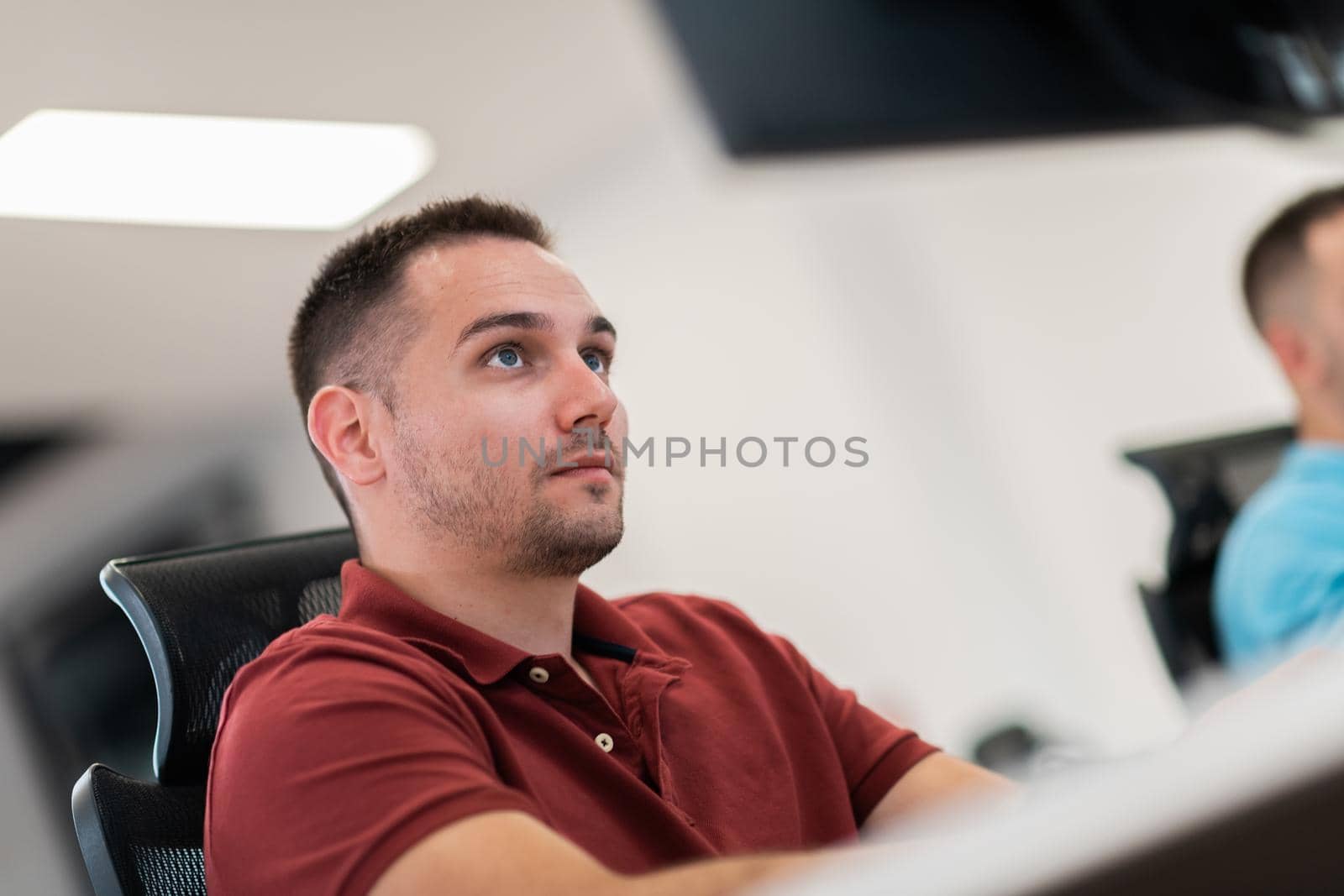 Casual business man working on desktop computer in modern open plan startup office interior. Selective focus by dotshock