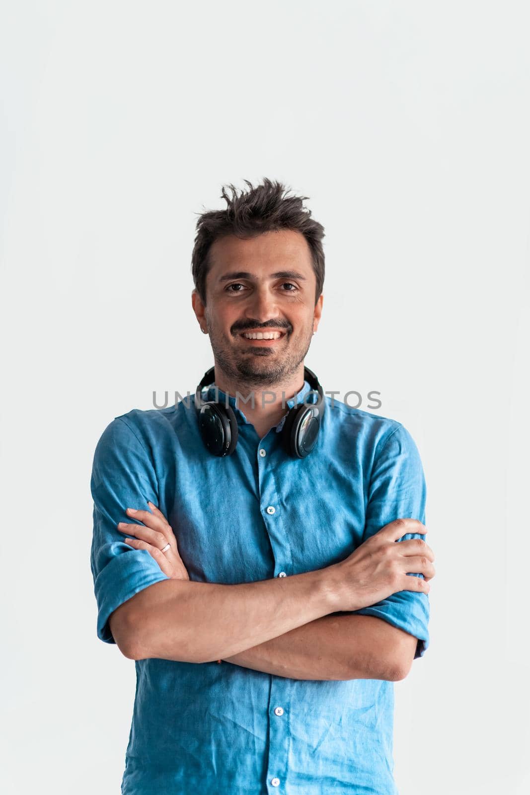 Formal business male portrait. A confident successful casual businessman or manager stands in front of a white background, arms crossed, looking directly at the camera and smiling friendly. High quality photography by dotshock
