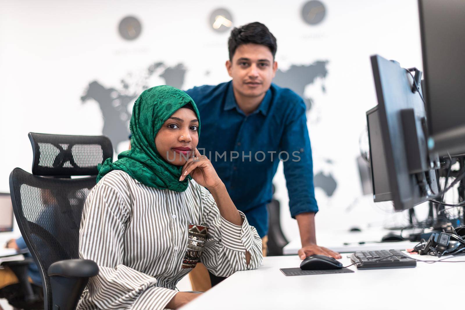 Multiethnic startup business team Arabian woman wearing a hijab on meeting in modern open plan office interior brainstorming, working on laptop and desktop computer. Selective focus. High-quality photo