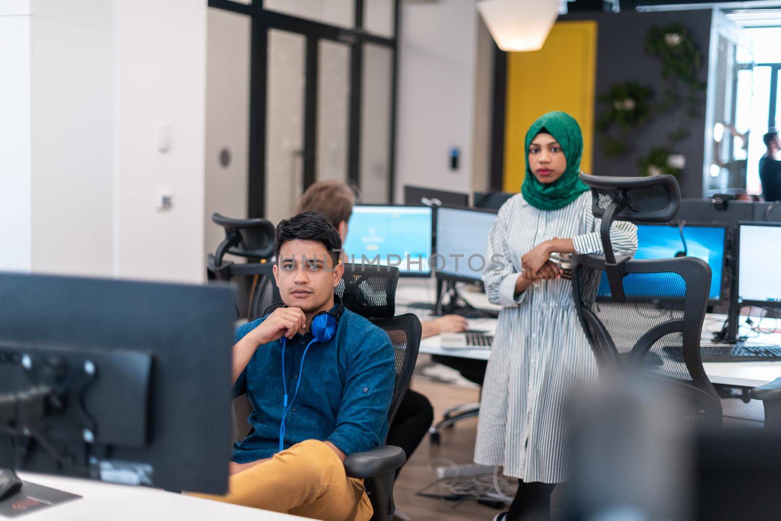 Multiethnic startup business team Arabian woman wearing a hijab on meeting in modern open plan office interior brainstorming, working on laptop and desktop computer. Selective focus by dotshock