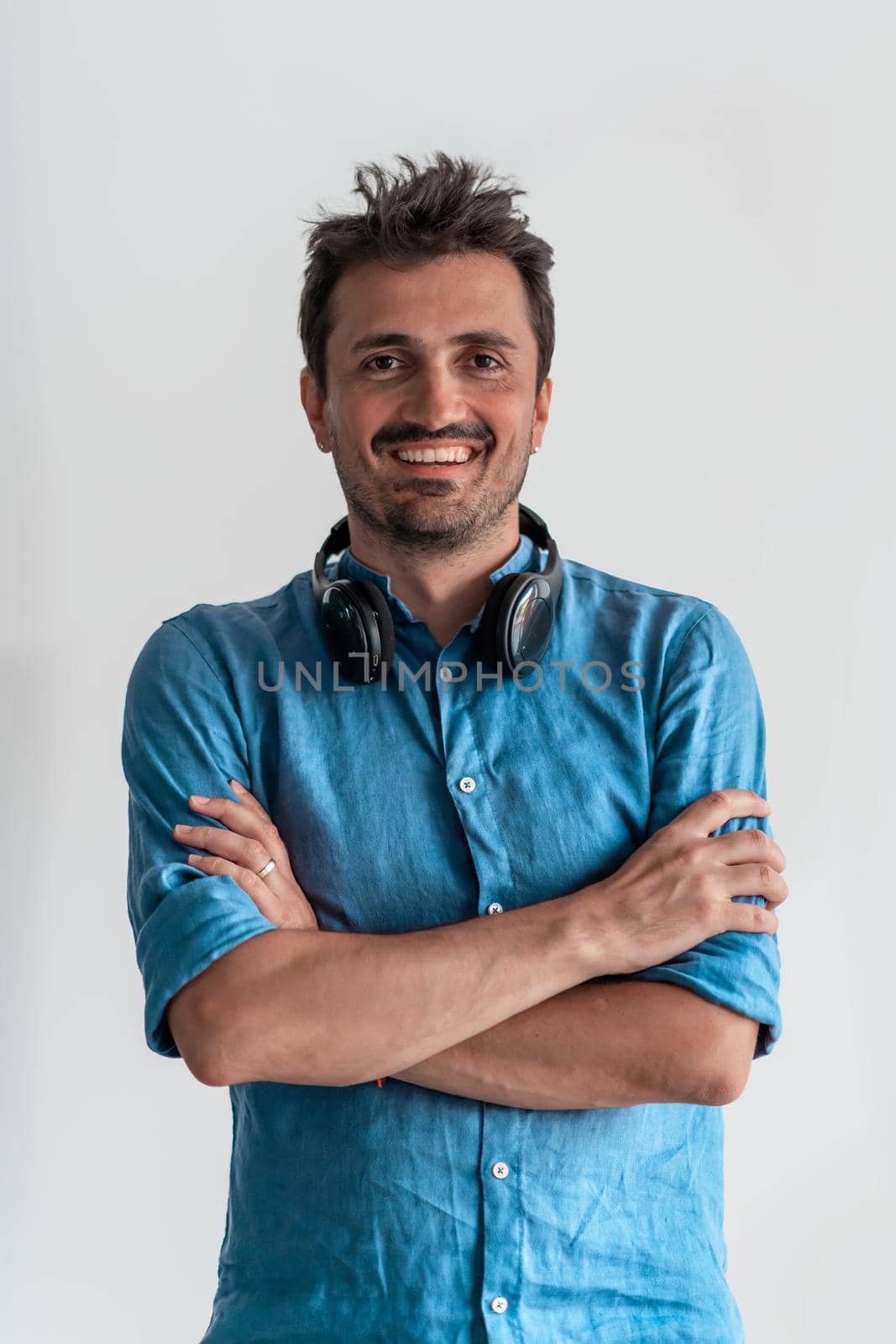 Formal business male portrait. A confident successful casual businessman or manager stands in front of a white background, arms crossed, looking directly at the camera and smiling friendly. High-quality photography.