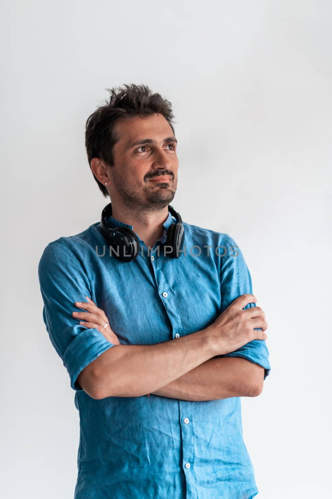 Formal business male portrait. A confident successful casual businessman or manager stands in front of a white background, arms crossed, looking directly at the camera and smiling friendly. High-quality photography.