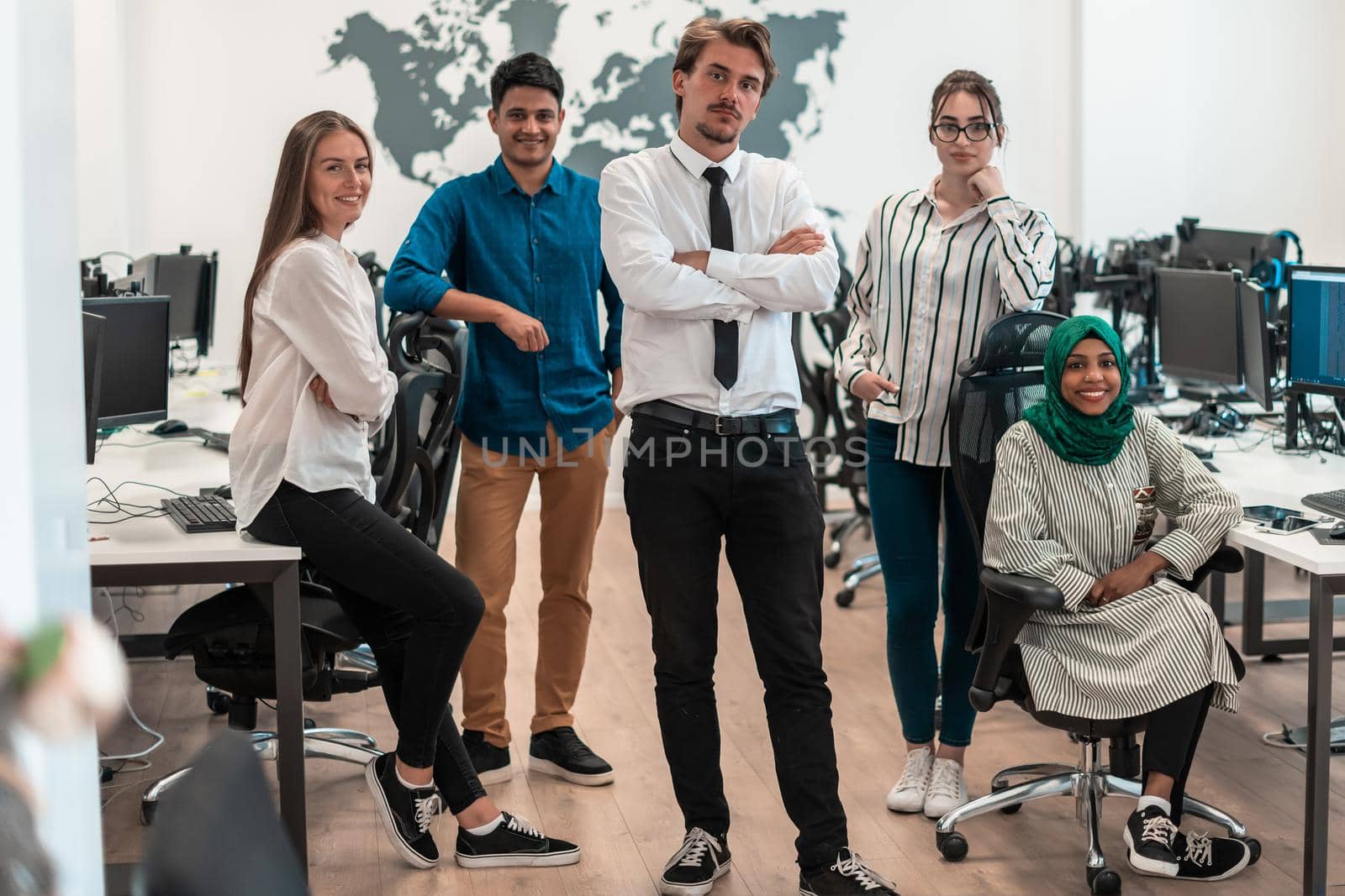 Portrait of young excited multiethnics business team of software developers standing and looking at the camera at modern startup office. High-quality photo