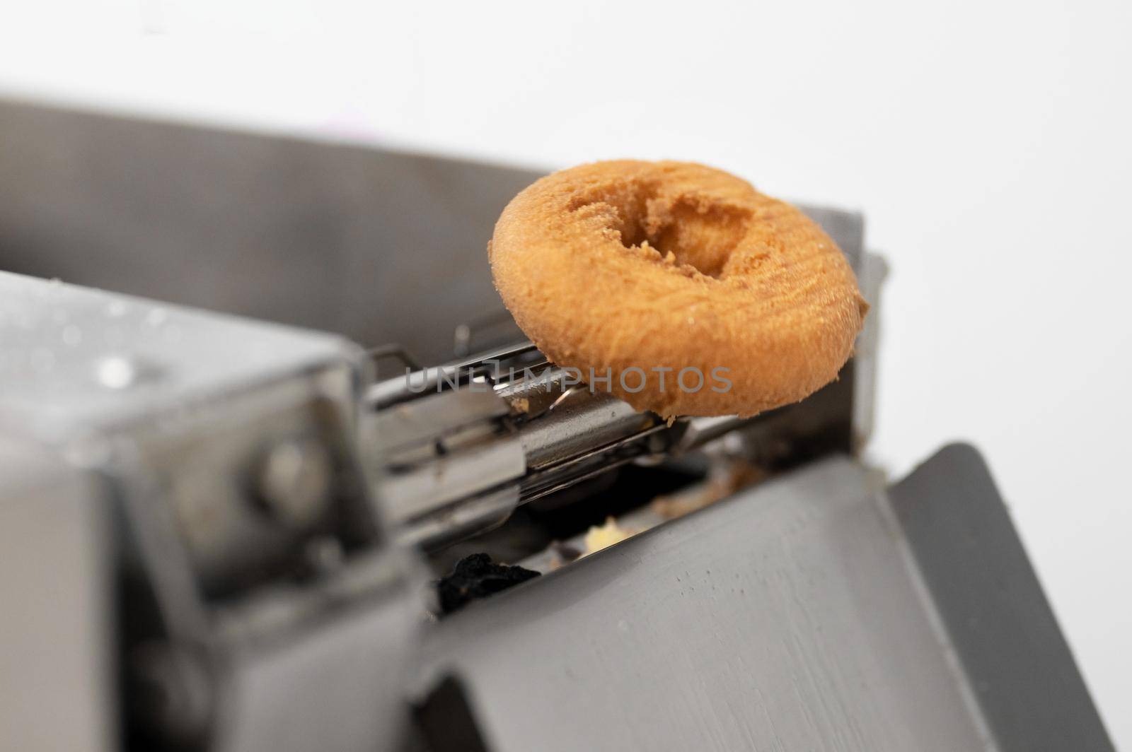 doughnuts or donut on conveyor belt in factory, a type of fried dough confectionery or dessert food. by HERRAEZ