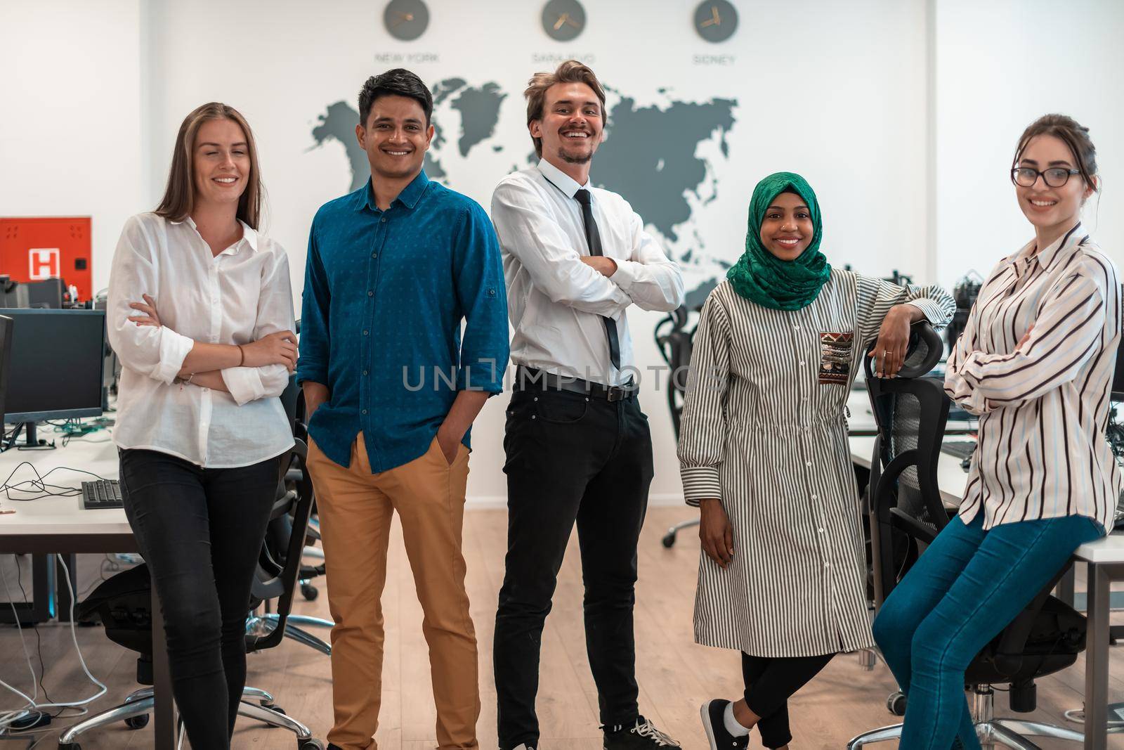 Portrait of young excited multiethnics business team of software developers standing and looking at the camera at modern startup office. High-quality photo