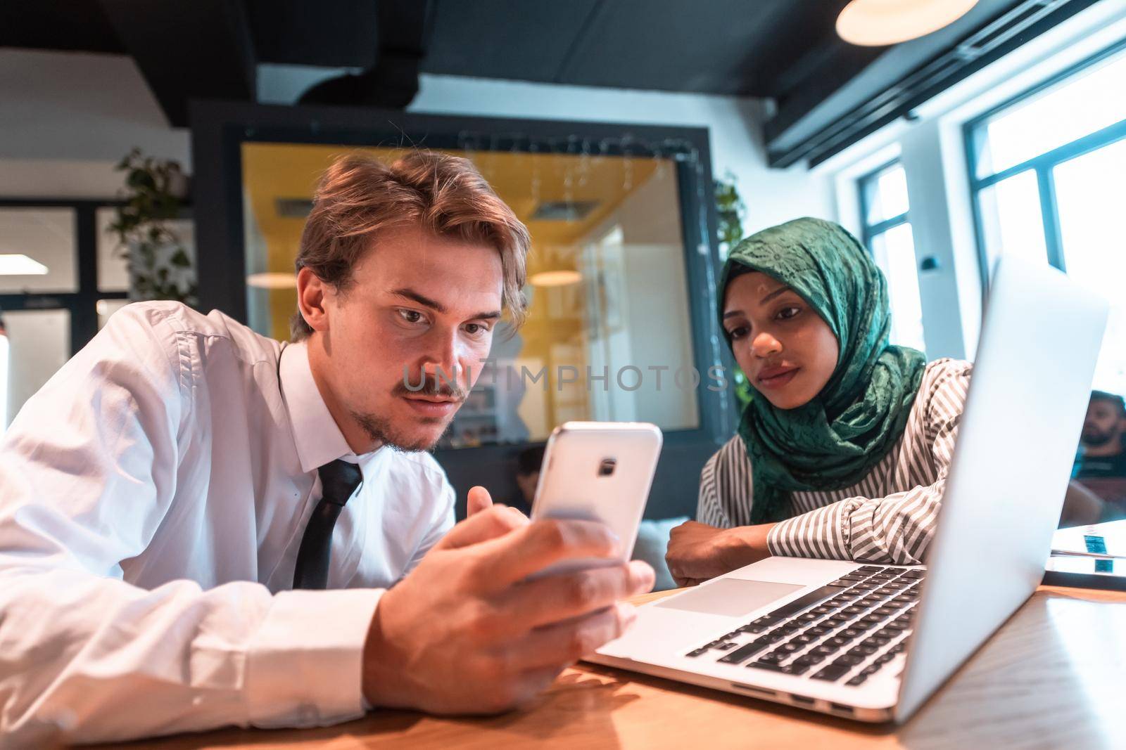 International multicultural business team.A young business man and woman sit in a modern relaxation space and talk about a new business. by dotshock