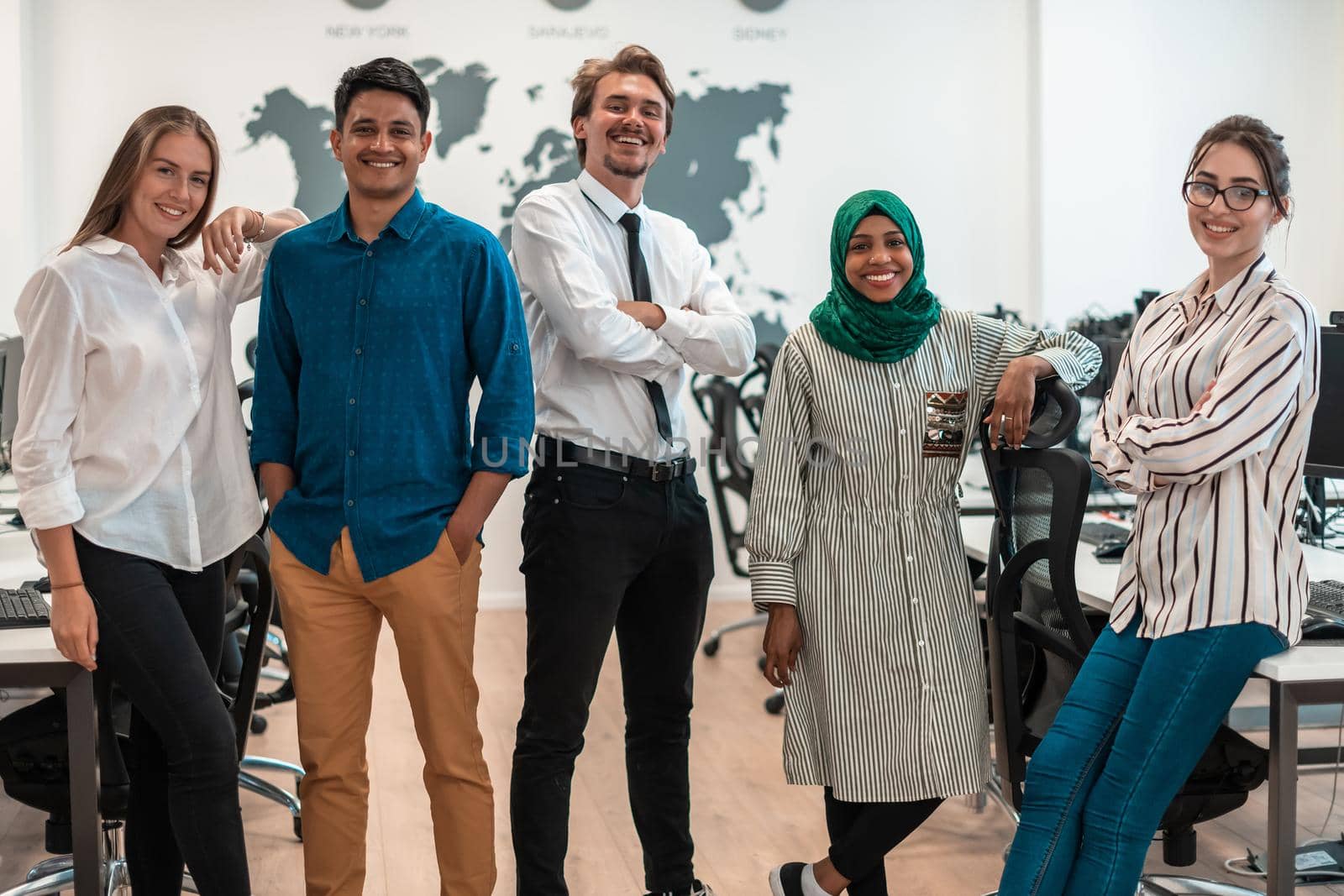 Portrait of young excited multiethnics business team of software developers standing and looking at the camera at modern startup office. High-quality photo