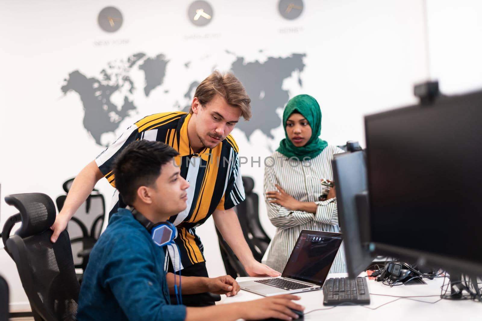 Multiethnic startup business team Arabian woman wearing a hijab on meeting in modern open plan office interior brainstorming, working on laptop and desktop computer. Selective focus by dotshock