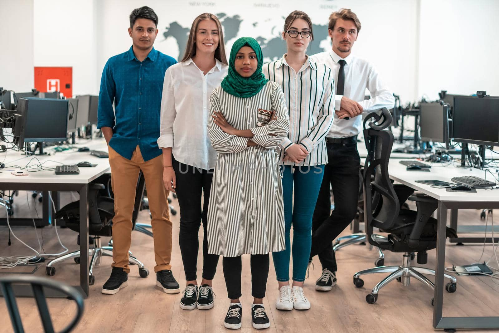 Portrait of young excited multiethnics business team of software developers standing and looking at the camera at modern startup office. High-quality photo