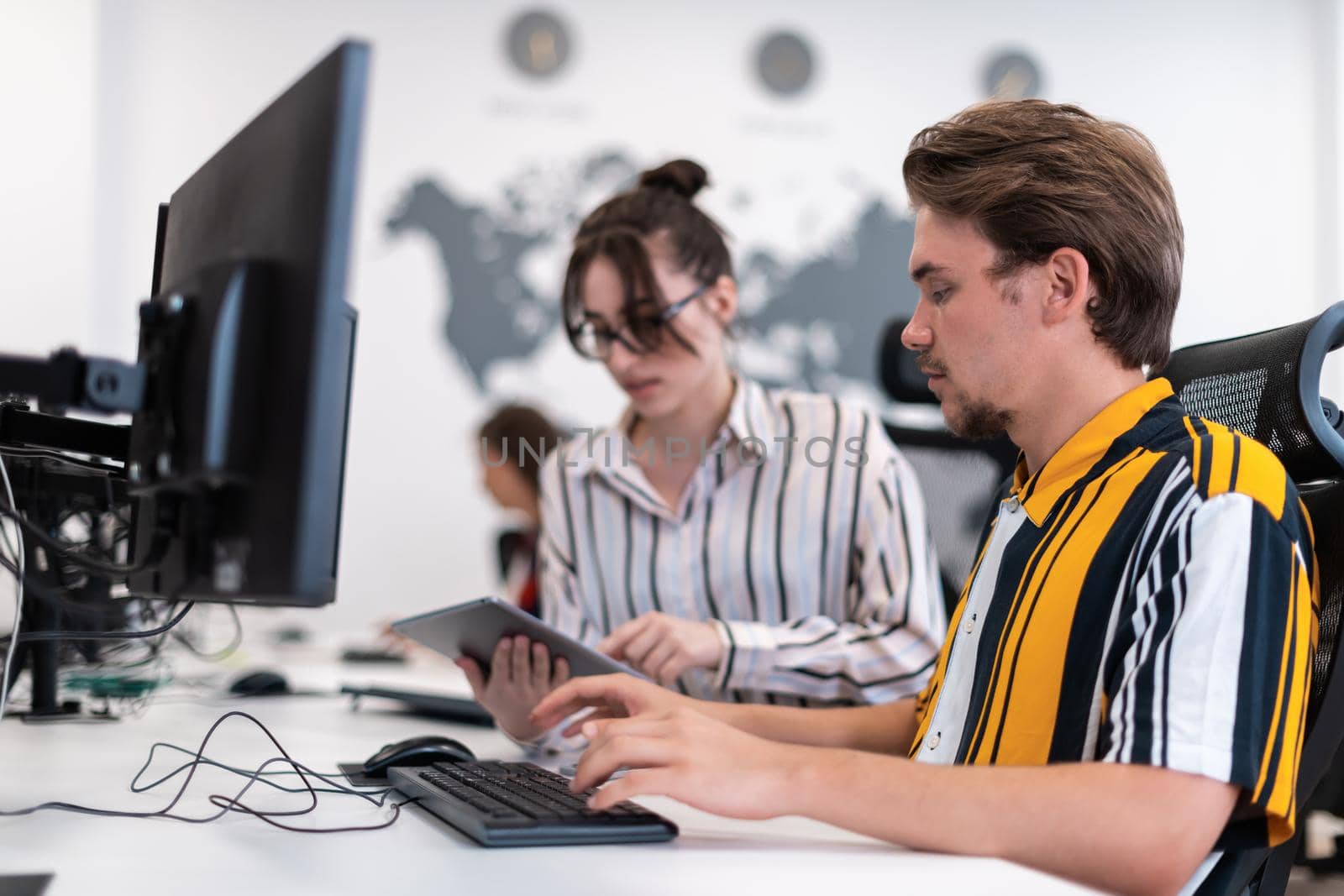 Business couple working together on project using tablet and desktop computer at modern open plan startup office. Selective focus by dotshock