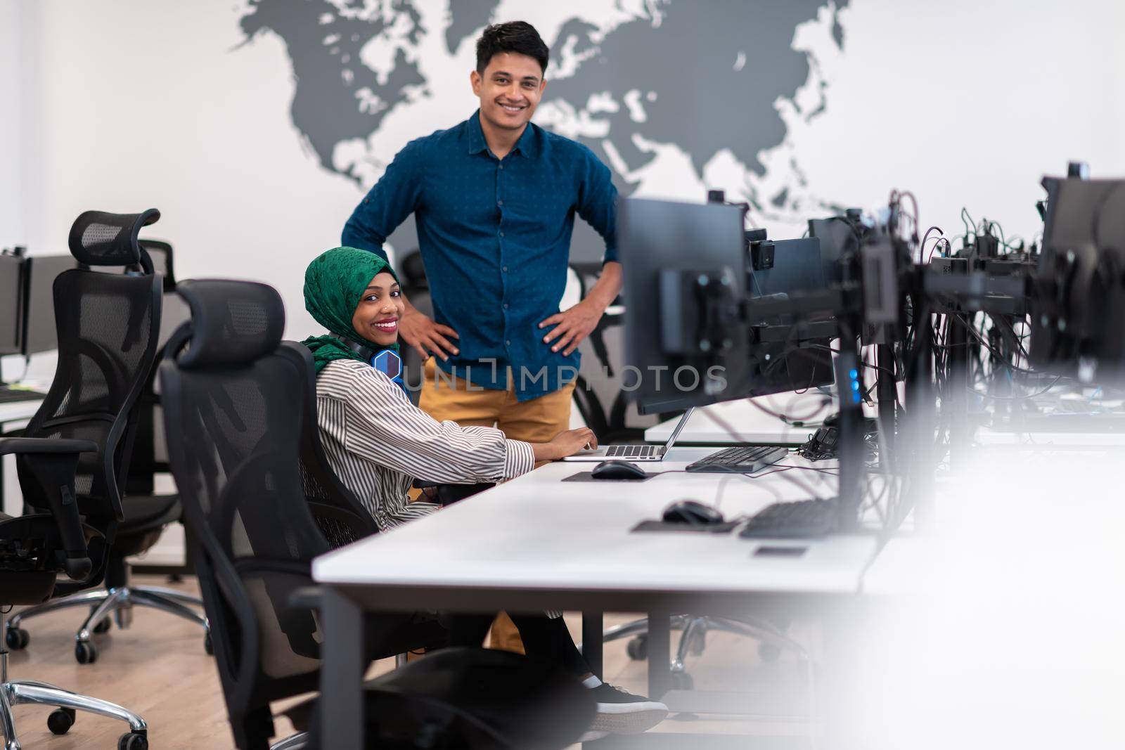 Multiethnic startup business team Arabian woman wearing a hijab on meeting in modern open plan office interior brainstorming, working on laptop and desktop computer. Selective focus. High-quality photo