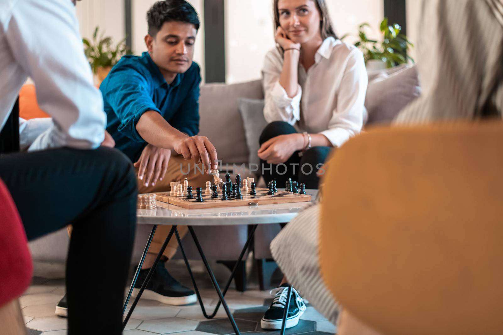 Multiethnic group of business people playing chess while having a break in relaxation area at modern startup office. Selective focus by dotshock