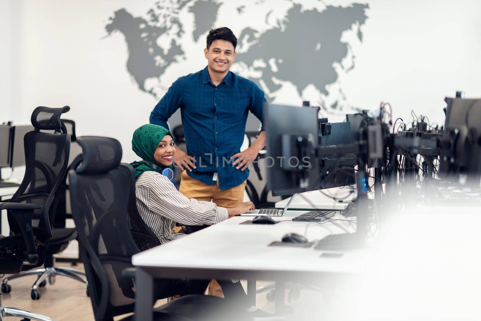 Multiethnic startup business team woman wearing a hijab on meeting in modern open plan office interior brainstorming, working on laptop and desktop computer. Selective focus. High-quality photo