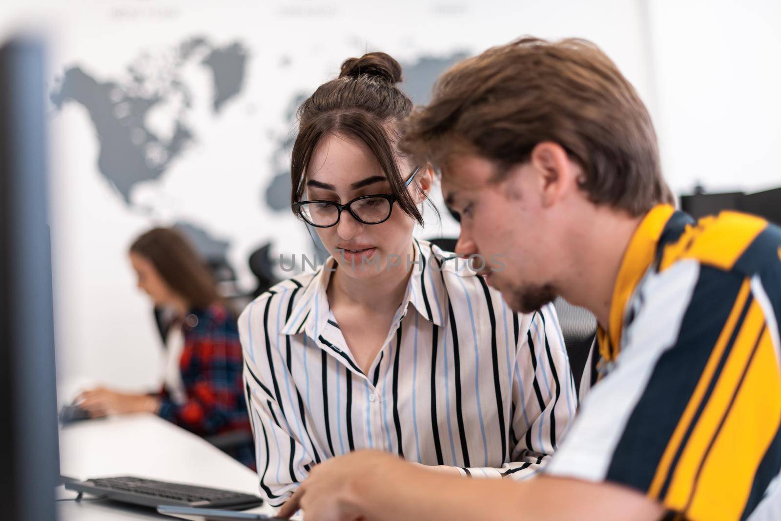 Business couple working together on a project using tablet and desktop computer at modern open plan startup office. Selective focus. High-quality photo