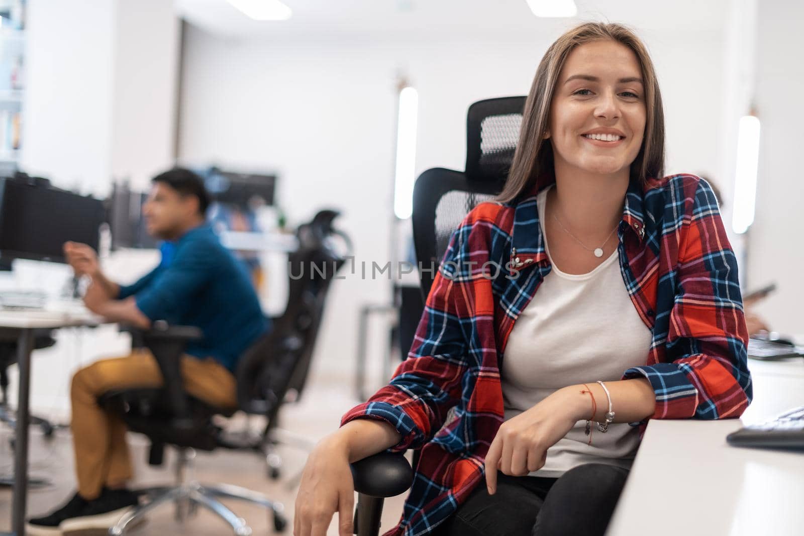 Casual business woman working on desktop computer in modern open plan startup office interior. Selective focus by dotshock