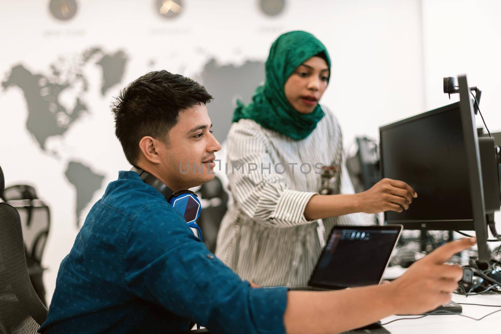 Multiethnic startup business team Arabian woman wearing a hijab on meeting in modern open plan office interior brainstorming, working on laptop and desktop computer. Selective focus by dotshock