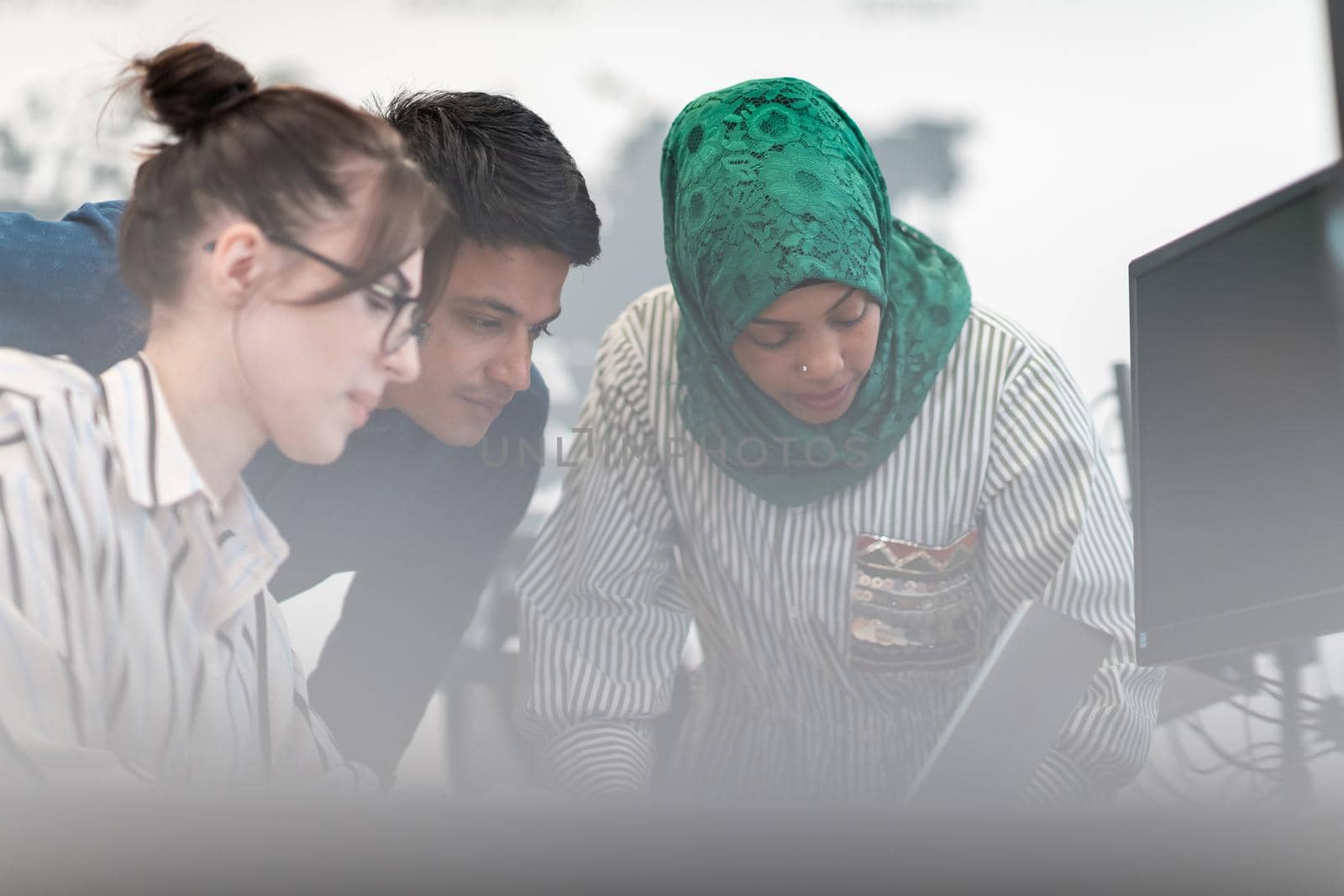 Multiethnic startup business team Arabian woman wearing a hijab on meeting in modern open plan office interior brainstorming, working on laptop and desktop computer. Selective focus. High-quality photo