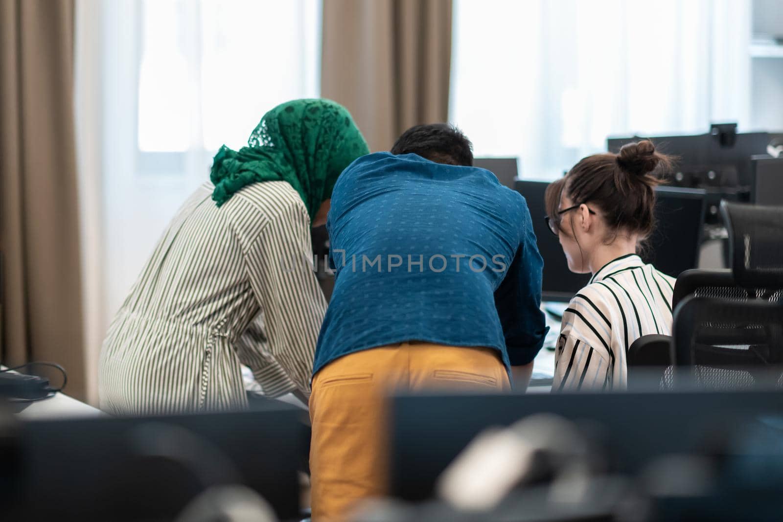 Multiethnic startup business team Arabian woman wearing a hijab on meeting in modern open plan office interior brainstorming, working on laptop and desktop computer. Selective focus. High-quality photo