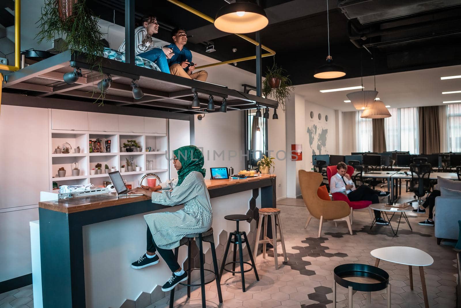 Group of casual multiethnic business people taking break from the work doing different things while enjoying free time in relaxation area at modern open plan startup office by dotshock