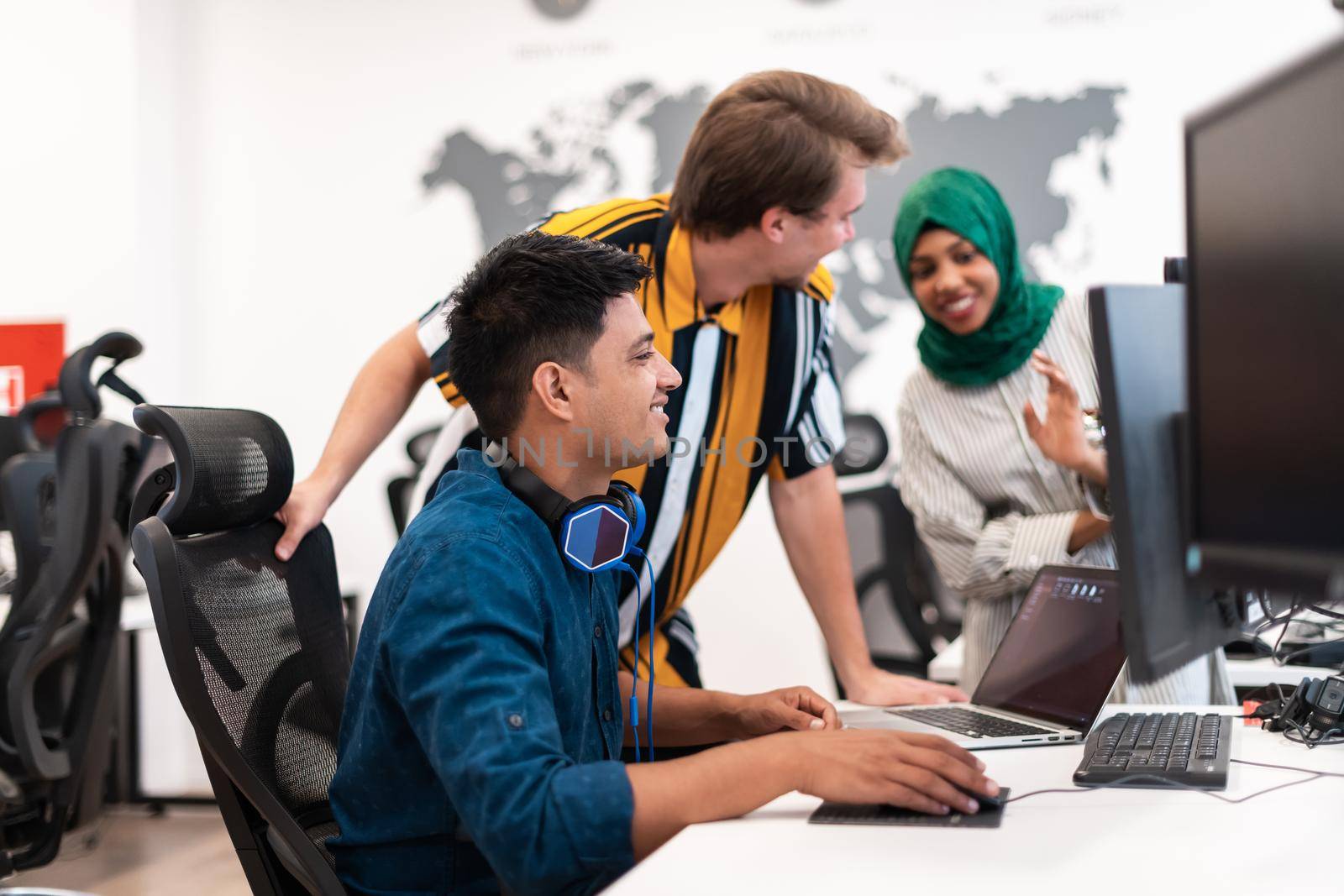 Multiethnic startup business team Arabian woman wearing a hijab on meeting in modern open plan office interior brainstorming, working on laptop and desktop computer. Selective focus. High-quality photo