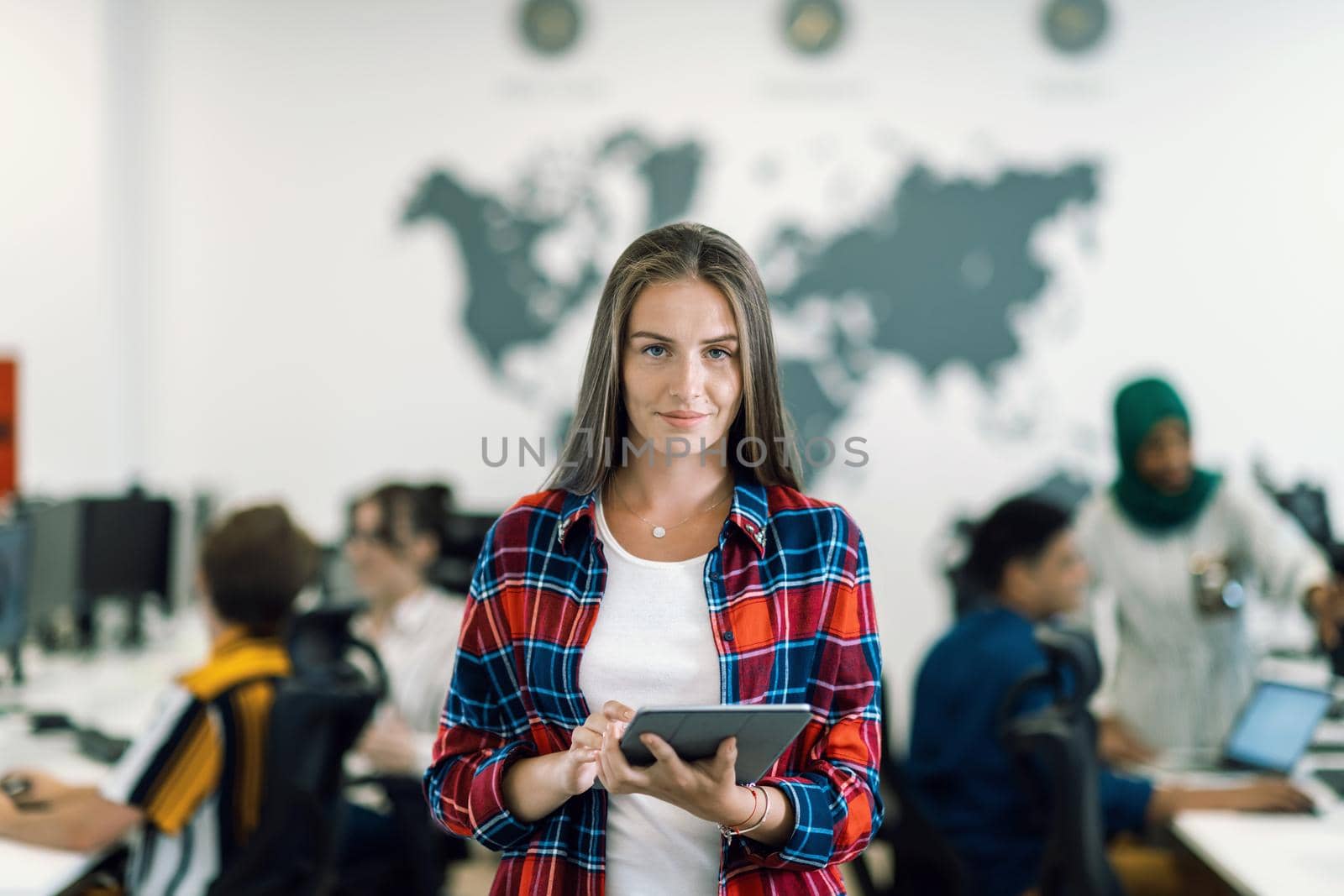 Portrait of businesswoman in casual clothes holding tablet computer at modern startup open plan office interior. Selective focus by dotshock