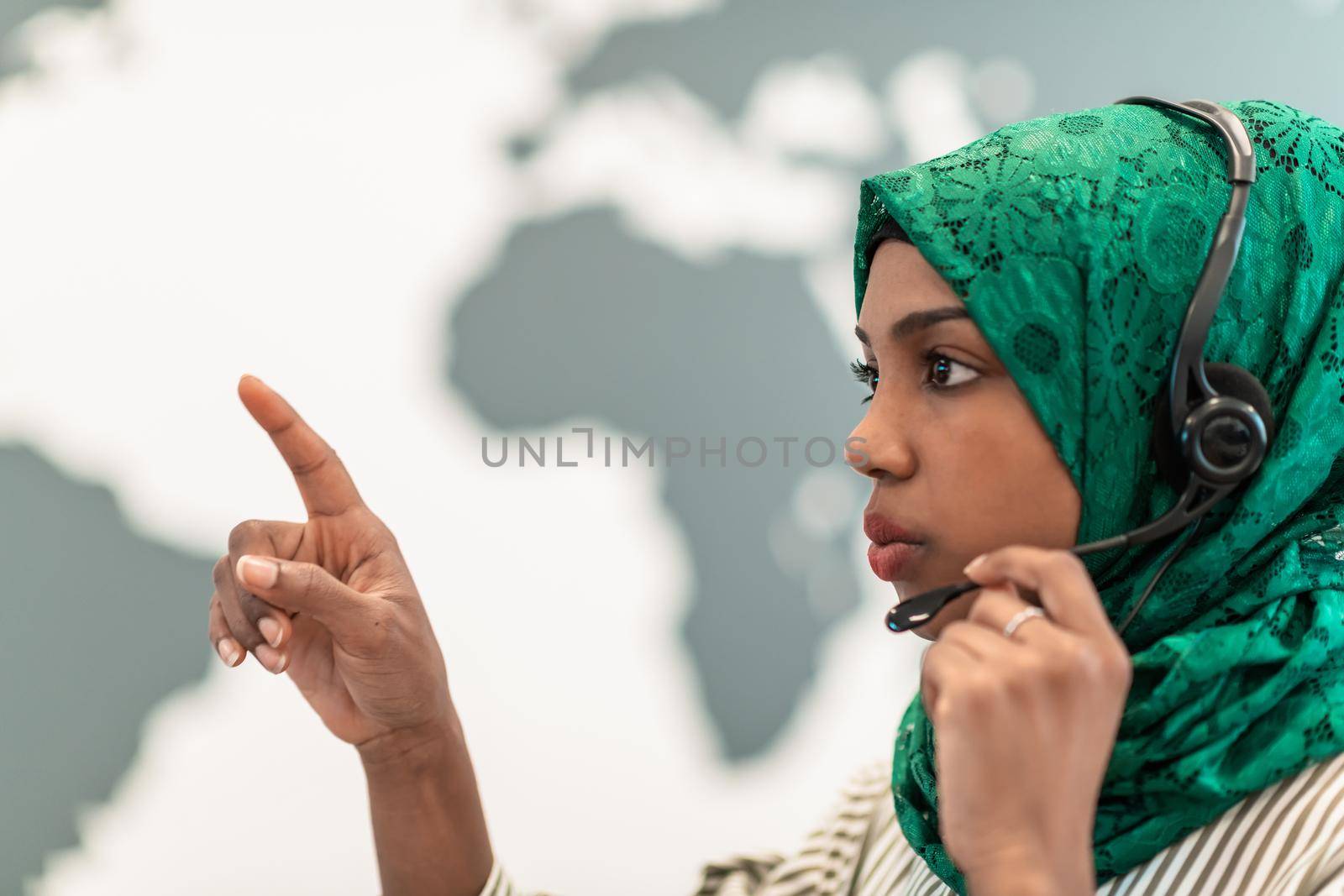 Afro Muslim female with green hijab scarf customer representative business woman with phone headset helping and supporting online with customer in modern call centre by dotshock