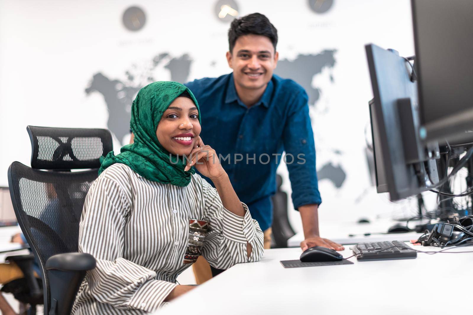 Multiethnic startup business team Arabian woman wearing a hijab on meeting in modern open plan office interior brainstorming, working on laptop and desktop computer. Selective focus by dotshock