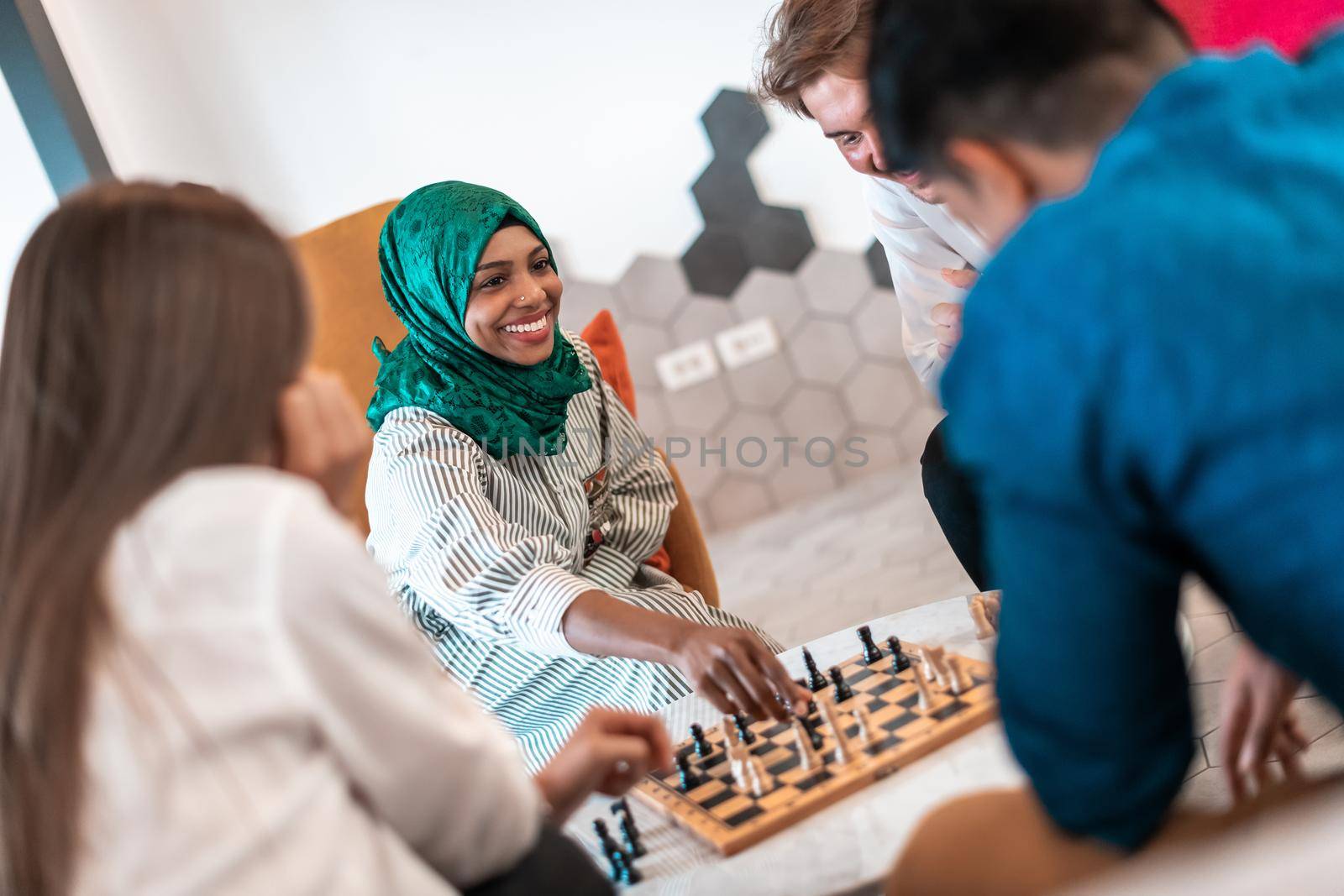 Multiethnic group of business people playing chess while having a break in relaxation area at modern startup office. Selective focus by dotshock