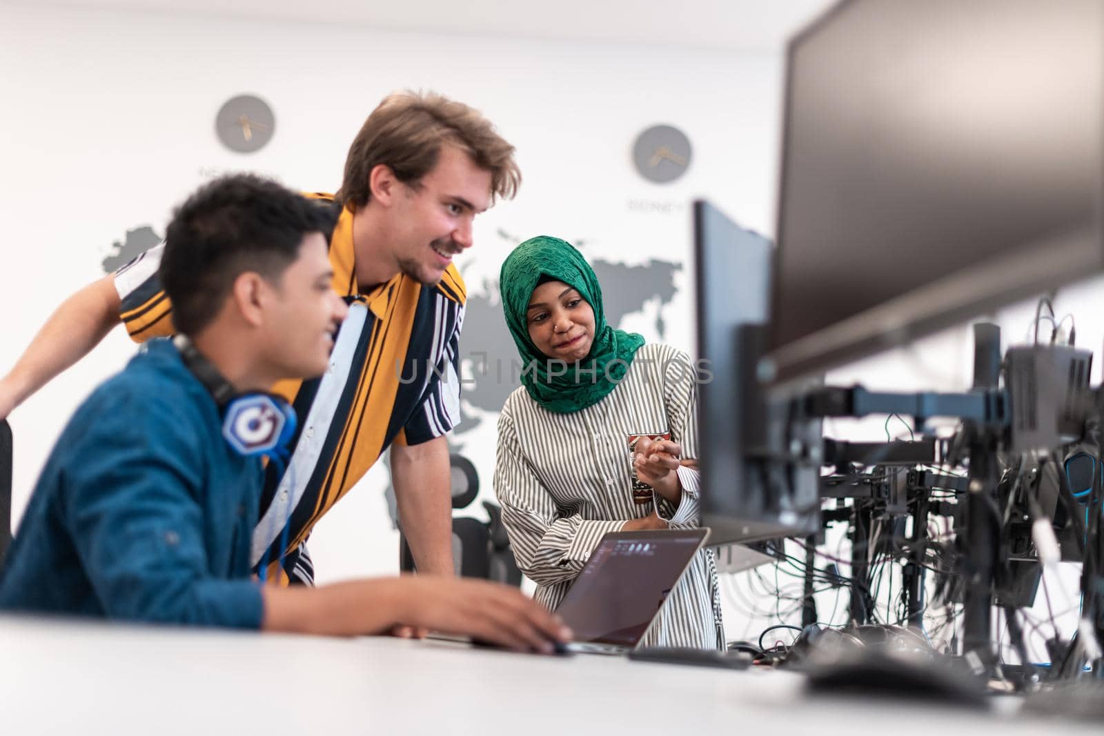 Multiethnic startup business team Arabian woman wearing a hijab on meeting in modern open plan office interior brainstorming, working on laptop and desktop computer. Selective focus. High-quality photo