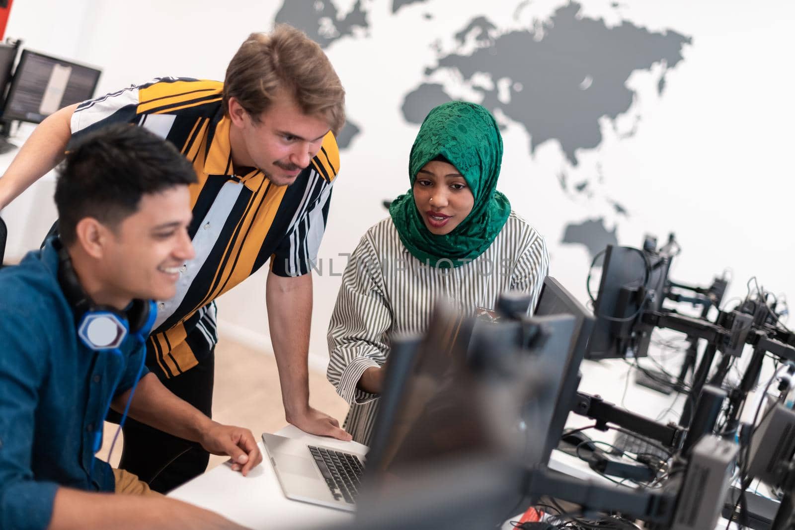 Multiethnic startup business team Arabian woman wearing a hijab on meeting in modern open plan office interior brainstorming, working on laptop and desktop computer. Selective focus. High-quality photo