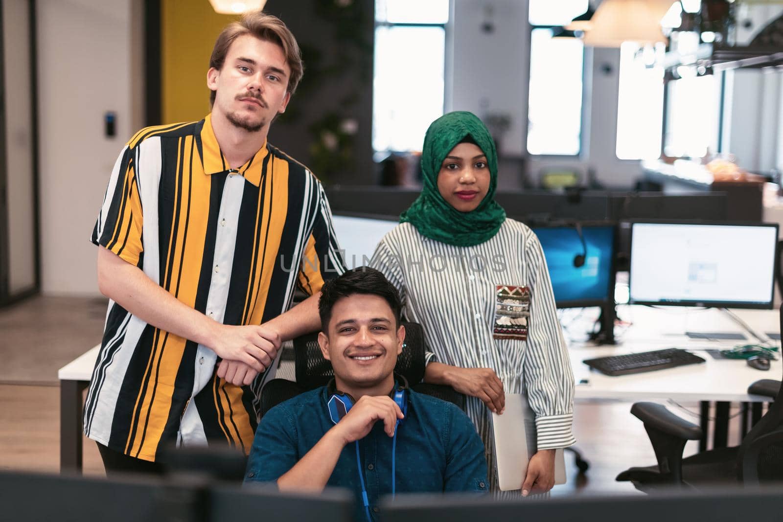 Multiethnic startup business team Arabian woman wearing a hijab on meeting in modern open plan office interior brainstorming, working on laptop and desktop computer. Selective focus by dotshock