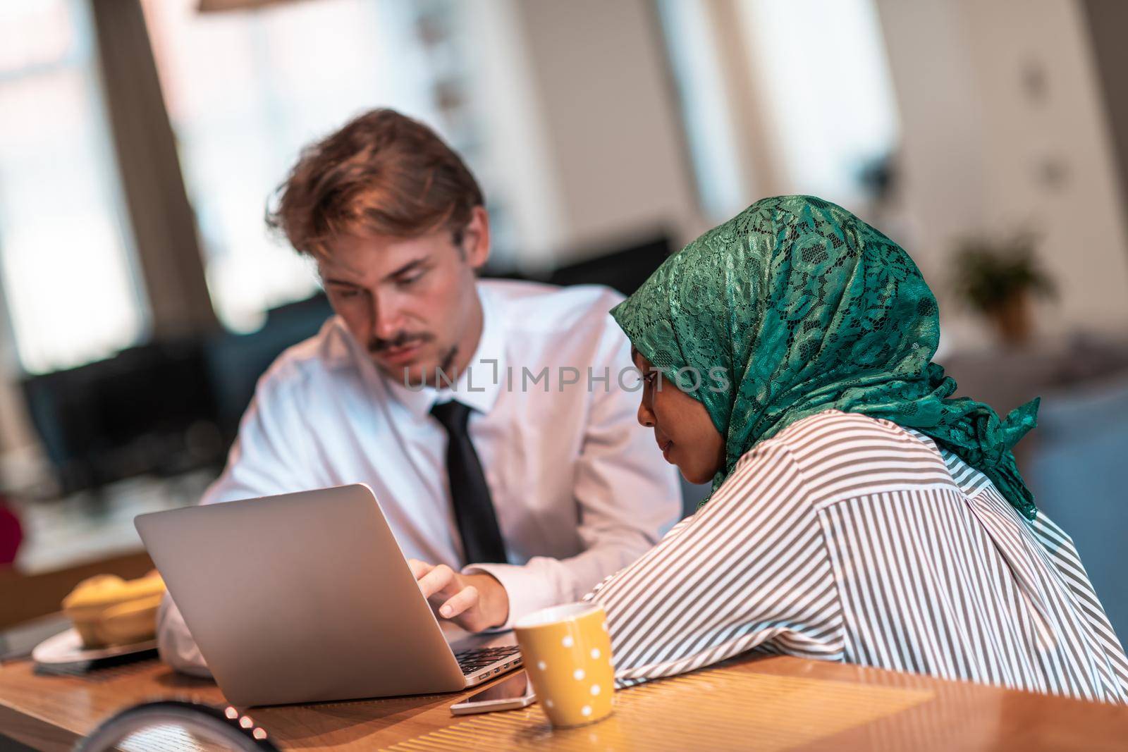International multicultural business team.Man and muslim woman with hijab working together using smartphone and laptop coxation area at modern open plan startup officemputer in rela by dotshock