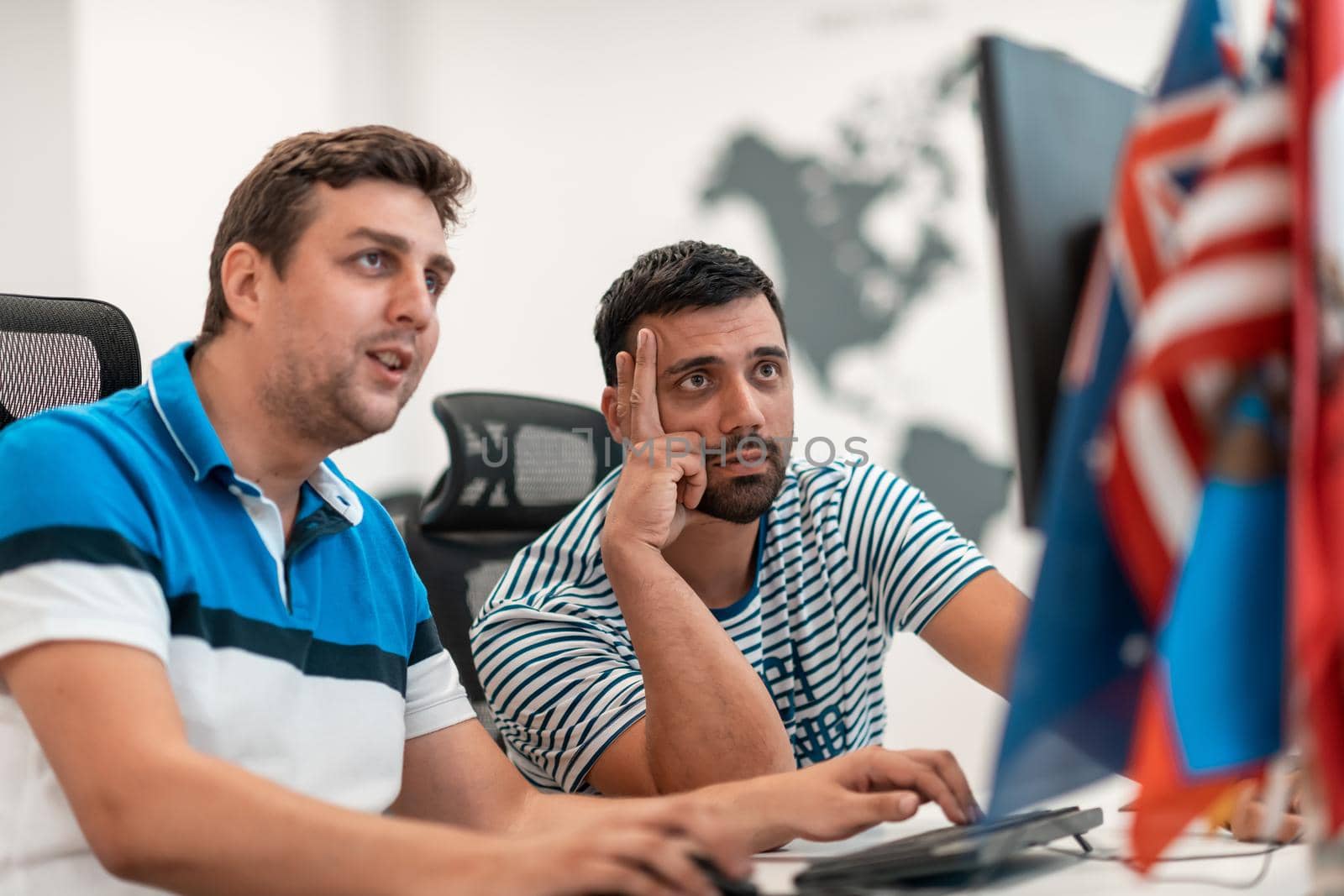 Group of Casual businessmen working on a desktop computer in modern open plan startup office interior. Selective focus. High-quality photo
