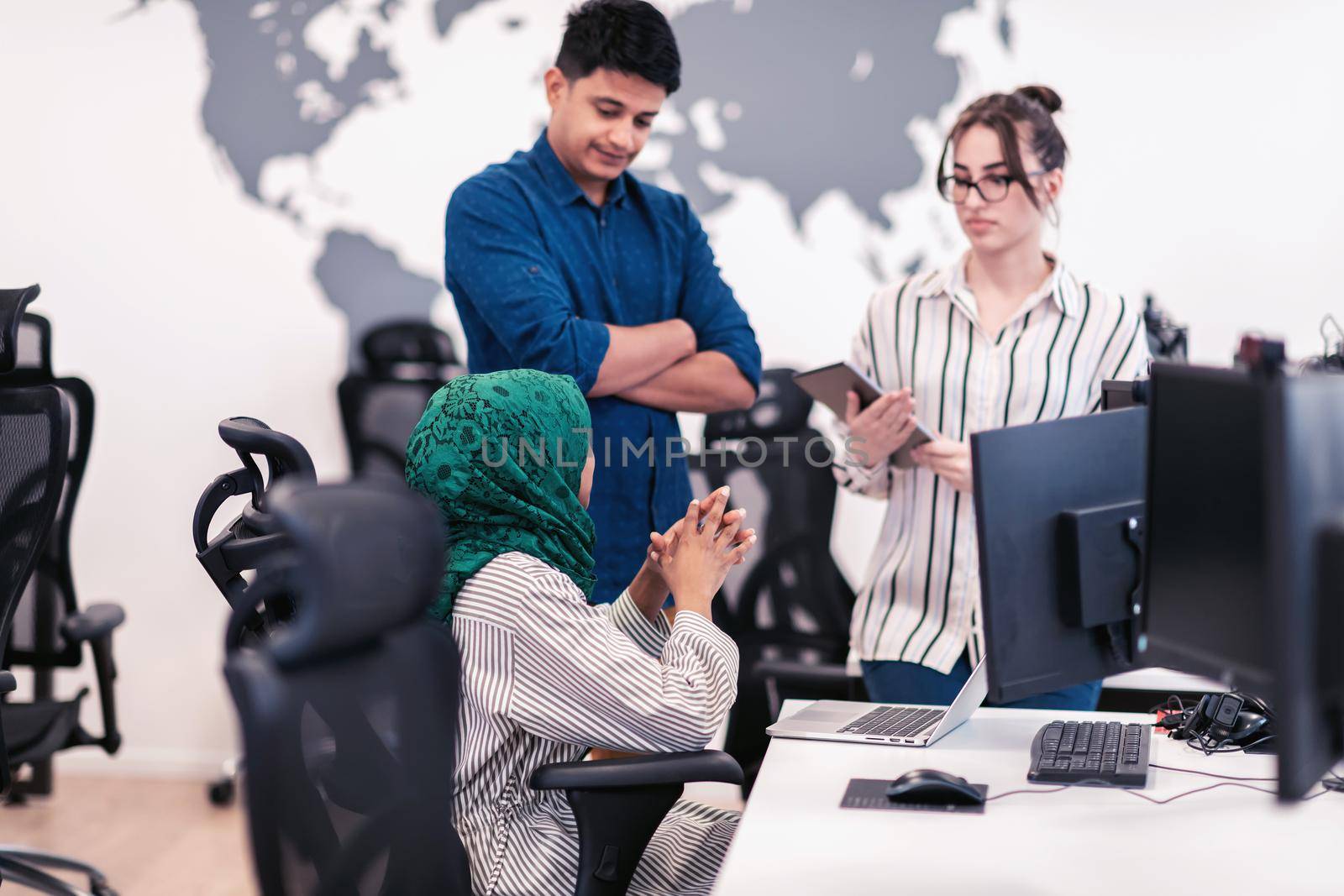 Multiethnic startup business team Arabian woman wearing a hijab on meeting in modern open plan office interior brainstorming, working on laptop and desktop computer. Selective focus. High-quality photo