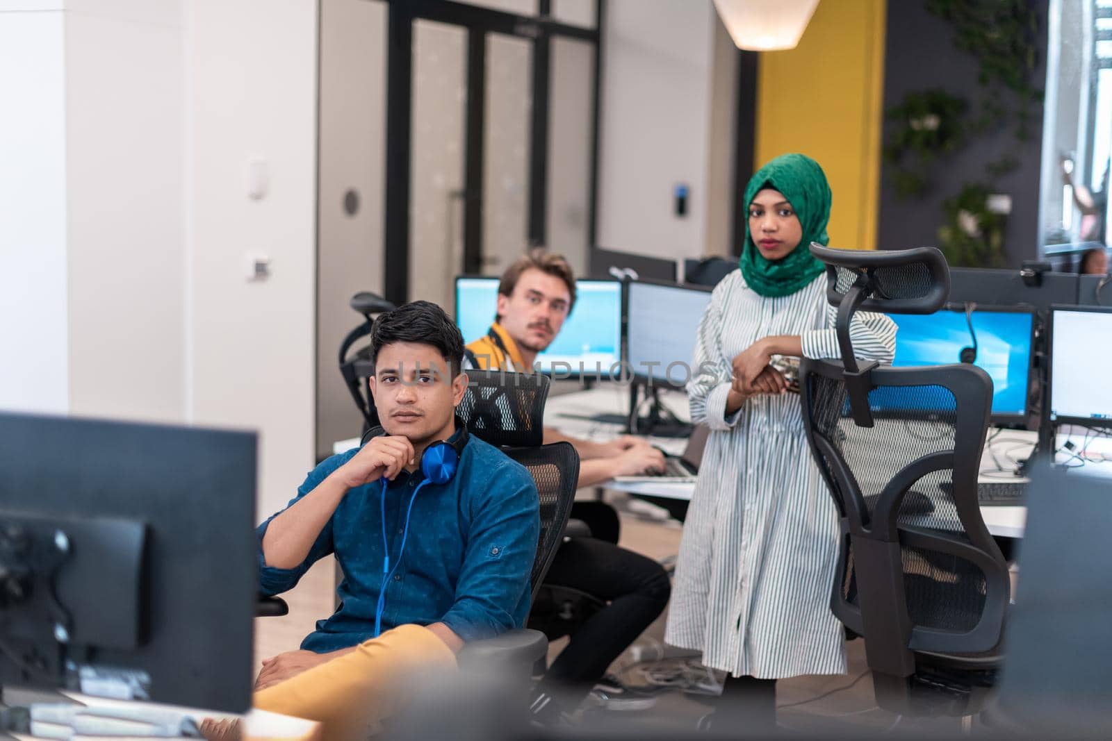 Multiethnic startup business team Arabian woman wearing a hijab on meeting in modern open plan office interior brainstorming, working on laptop and desktop computer. Selective focus by dotshock