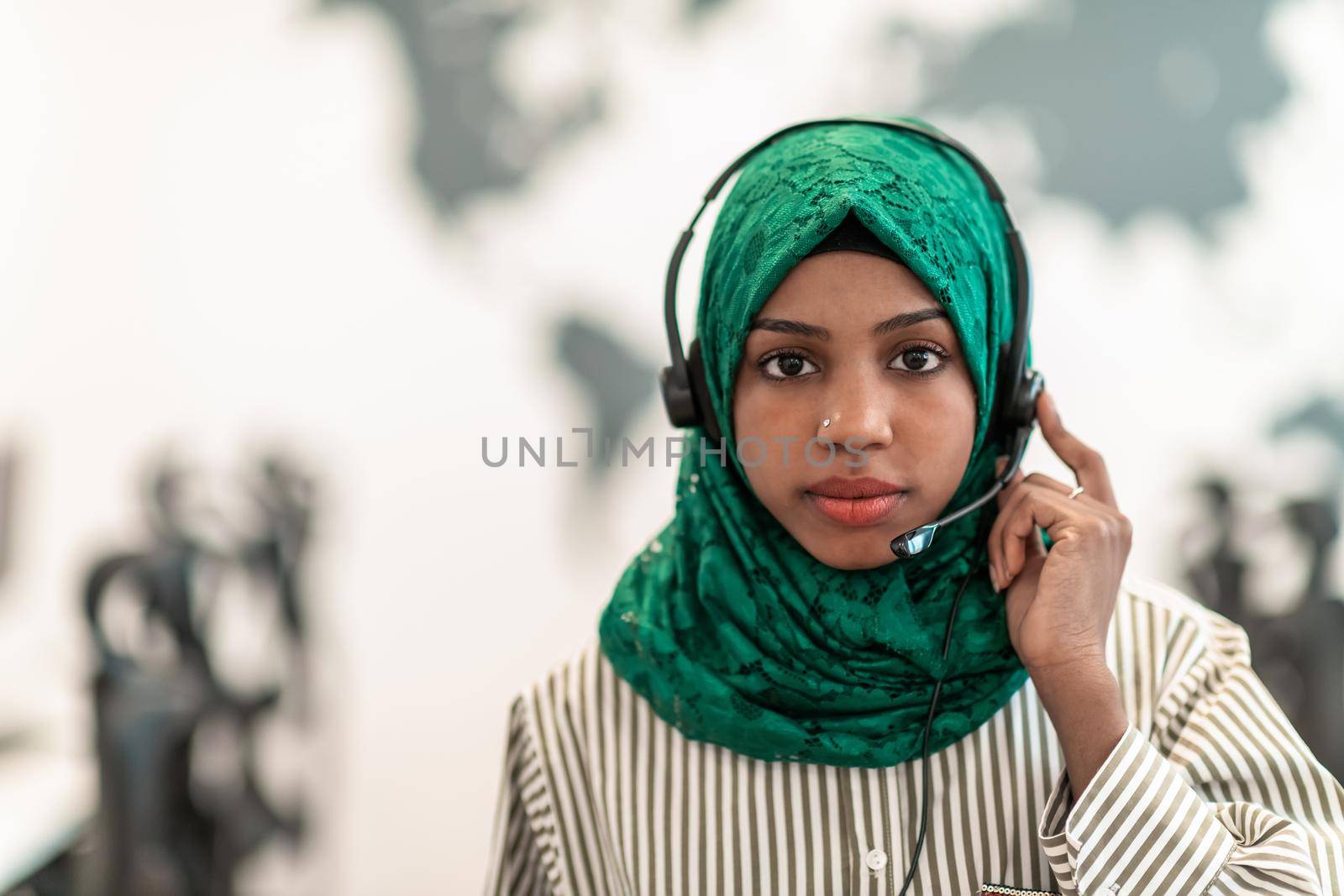 Afro Muslim female with green hijab scarf customer representative business woman with phone headset helping and supporting online with customer in modern call centre by dotshock