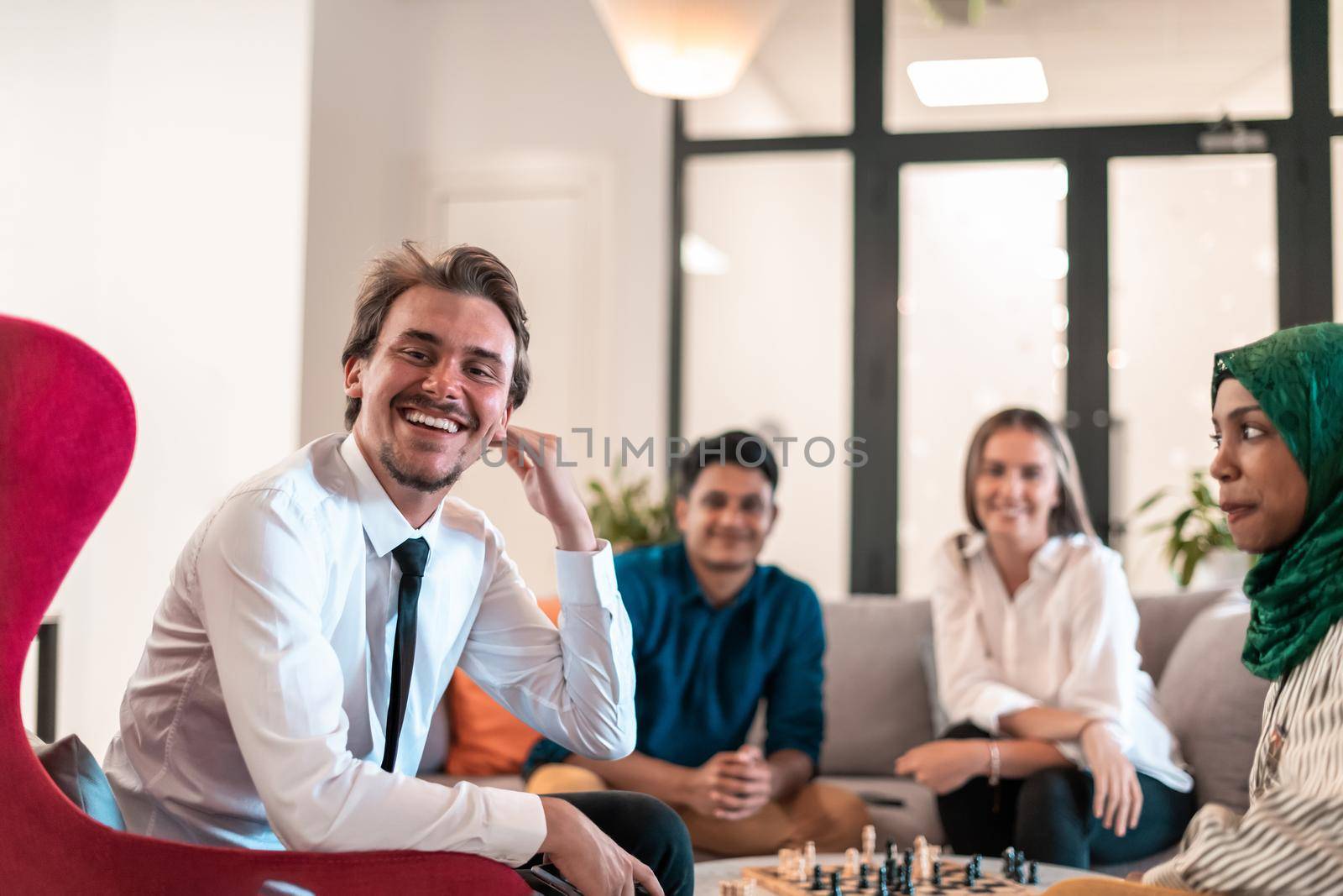 Multiethnic group of businesspeople playing chess while having a break in relaxation area at modern startup office. High-quality photo