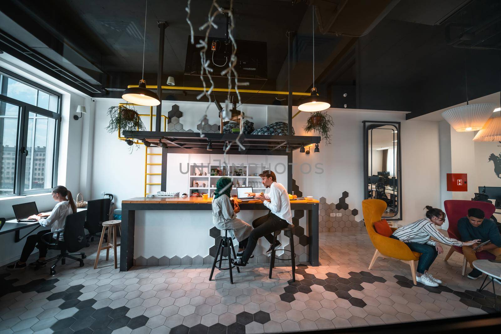 Group of casual multiethnic business people taking break from the work doing different things while enjoying free time in relaxation area at modern open plan startup office by dotshock