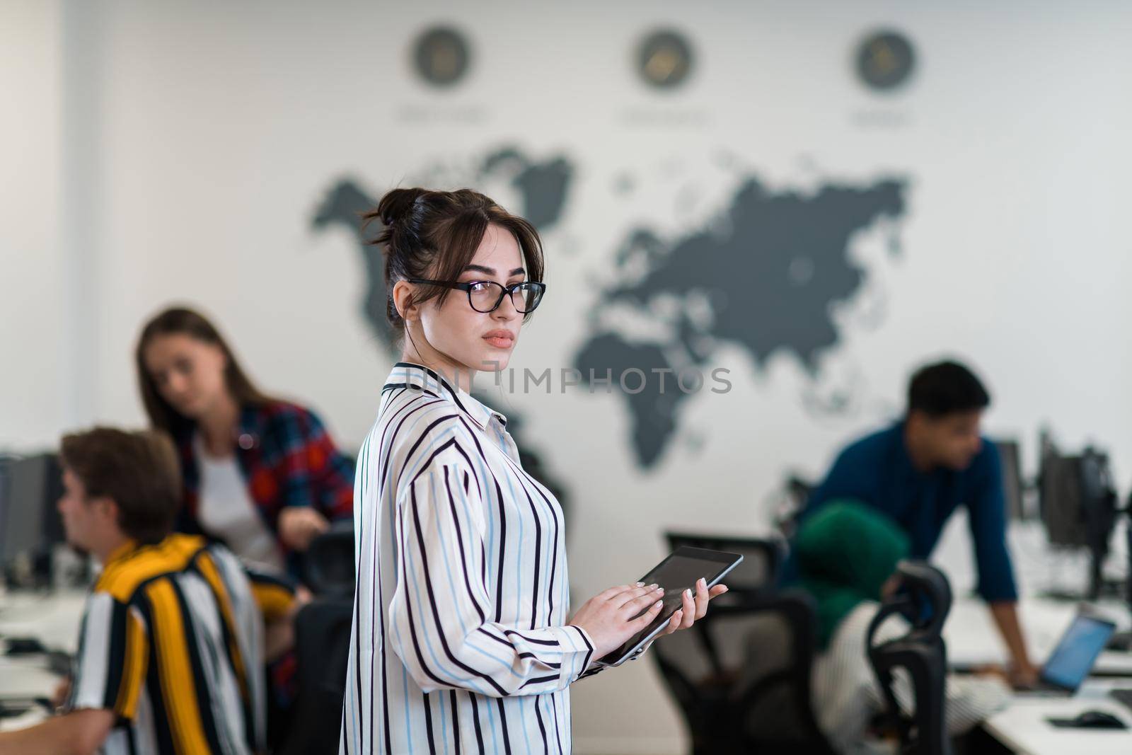 Portrait of businesswoman in casual clothes holding tablet computer at modern startup open plan office interior. Selective focus. High-quality photo