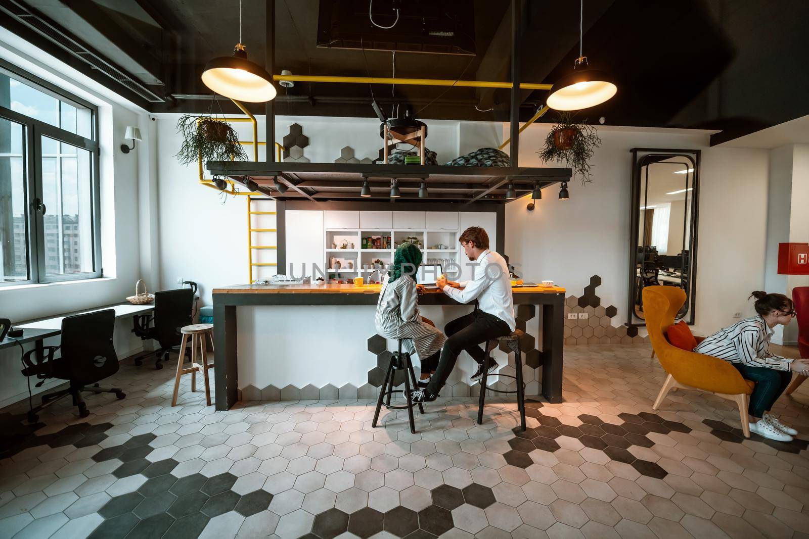 Group of casual multiethnic business people taking break from the work doing different things while enjoying free time in relaxation area at modern open plan startup office by dotshock