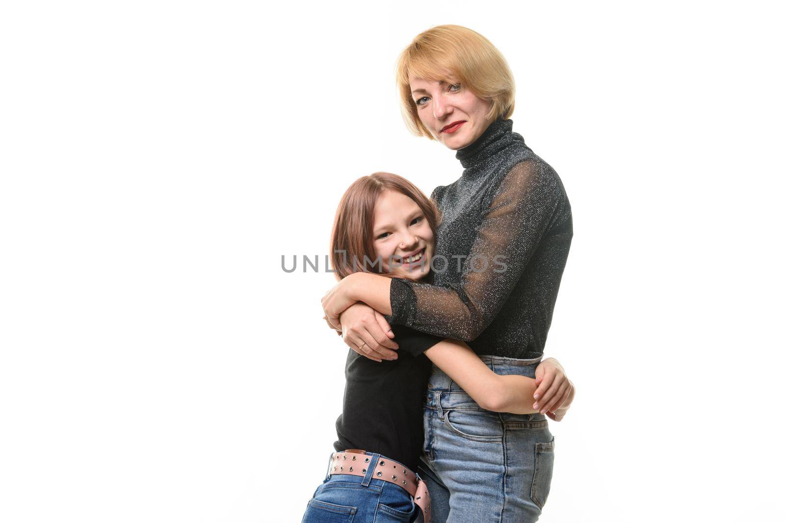 Happy daughter hugs her mother, both look joyfully into the frame, close-up portraita