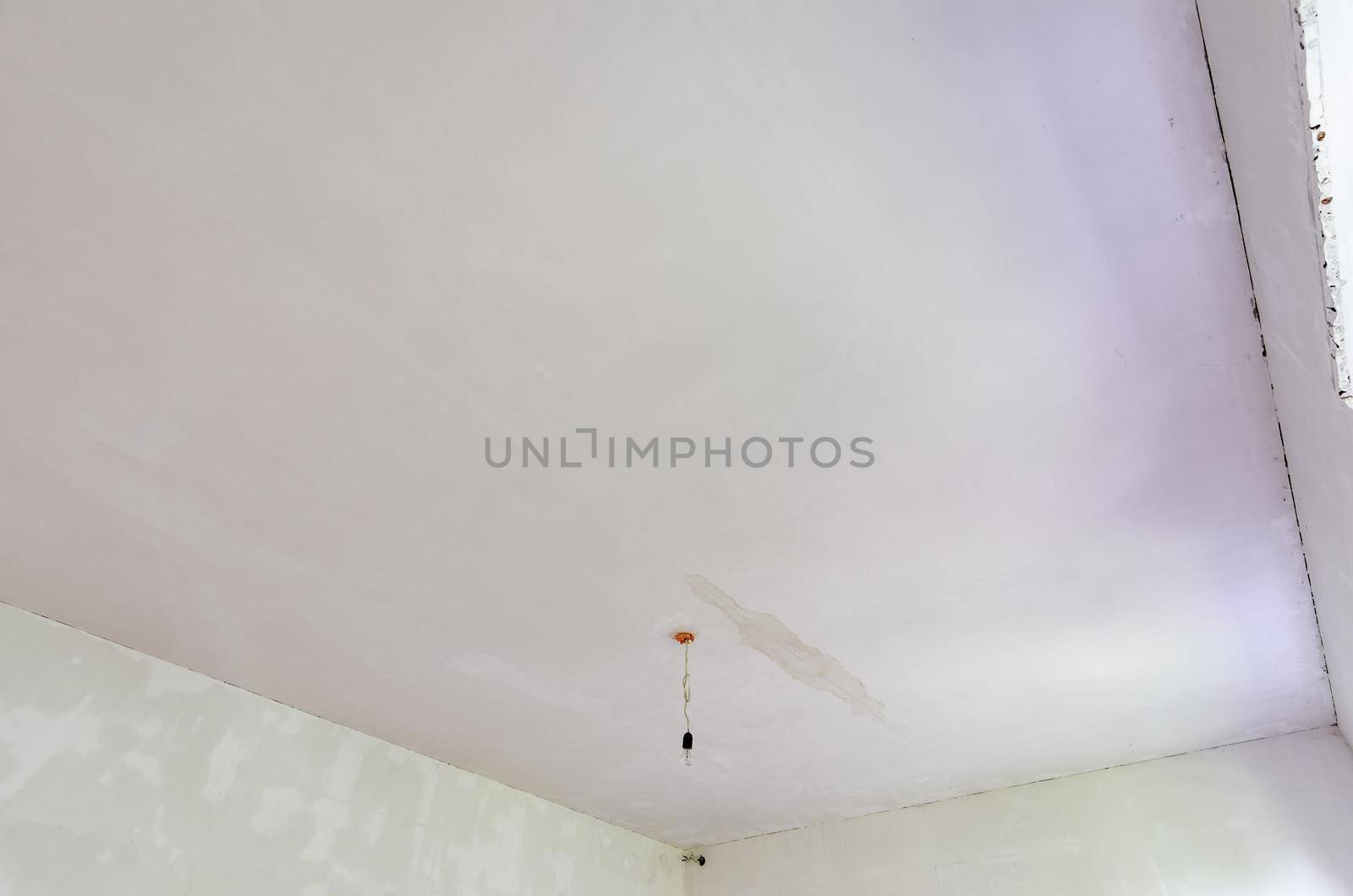 Plastered ceiling in the room, stains from flooding from above are visible on the ceiling a