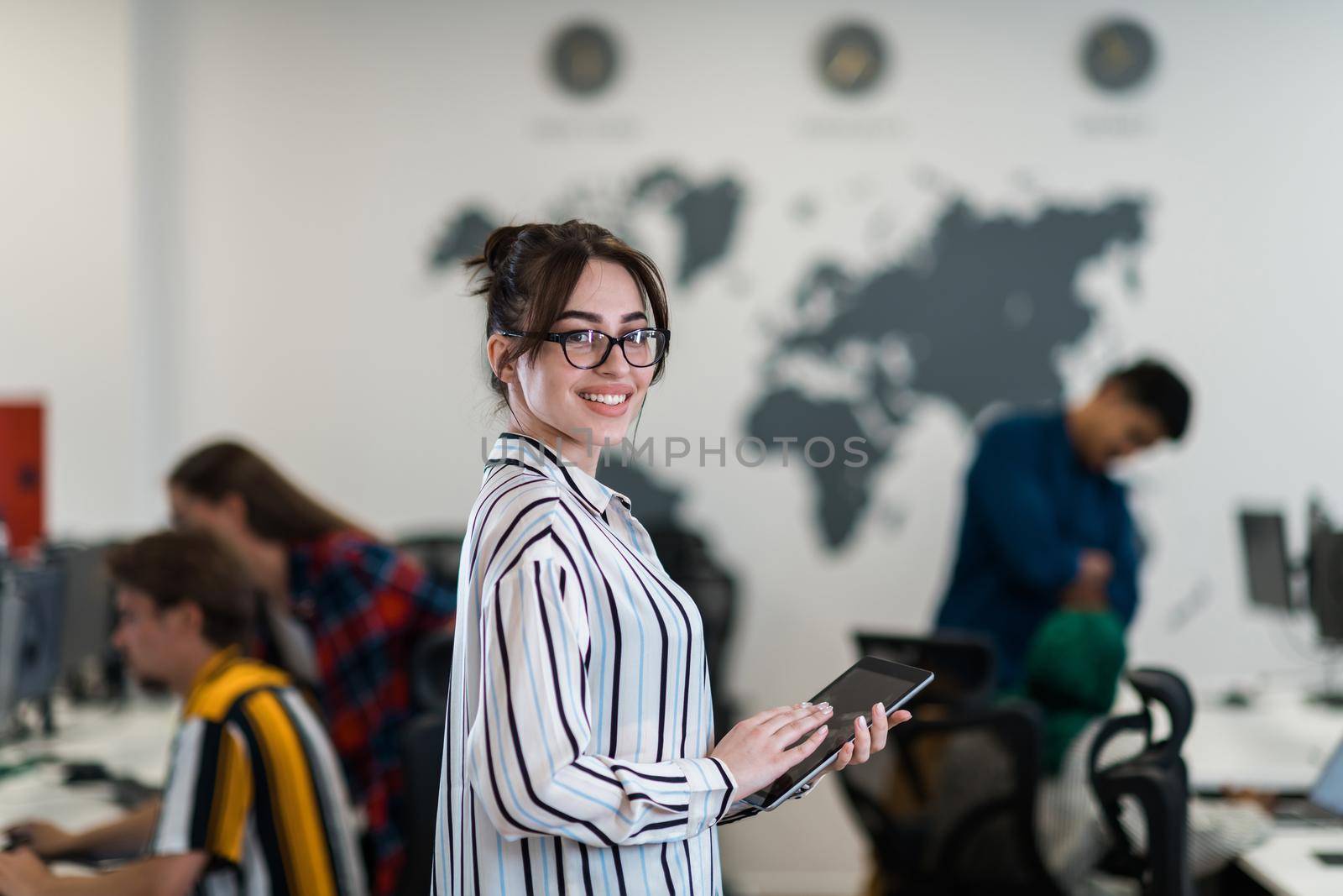 Portrait of businesswoman in casual clothes holding tablet computer at modern startup open plan office interior. Selective focus by dotshock