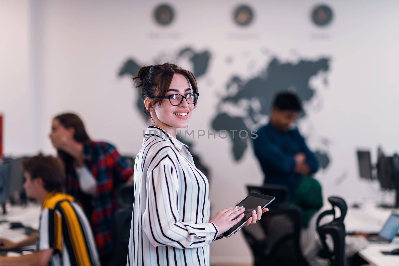 Portrait of businesswoman in casual clothes holding tablet computer at modern startup open plan office interior. Selective focus by dotshock