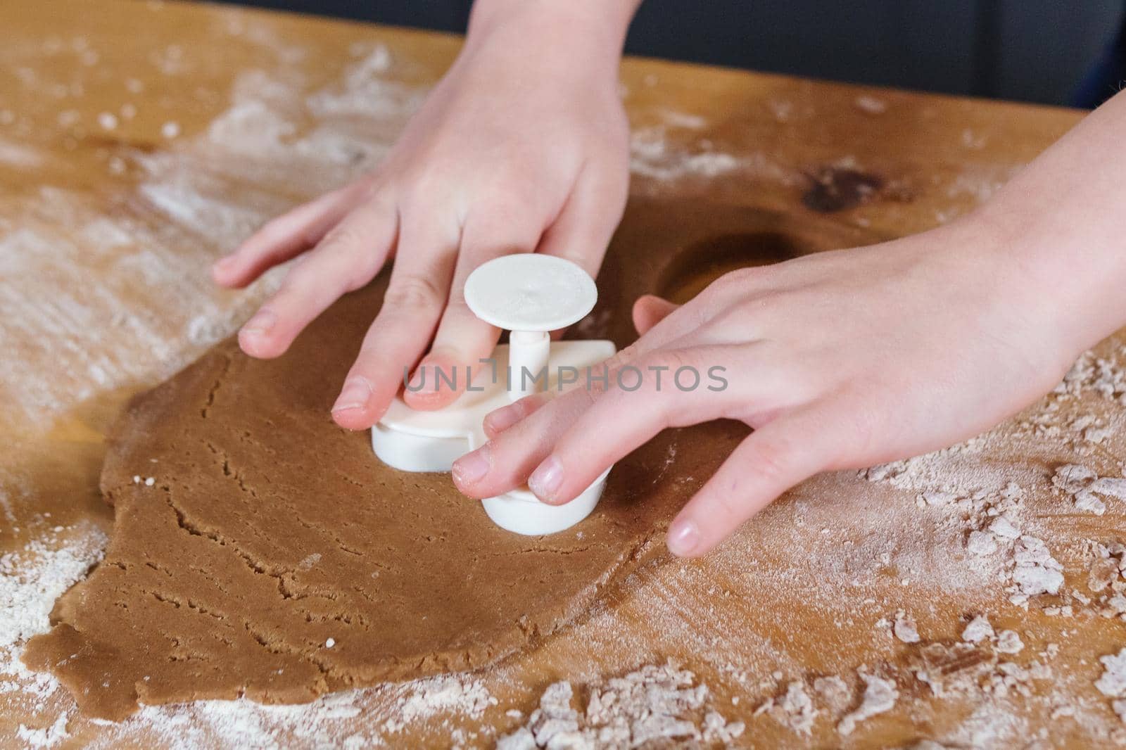 A little girl makes heart-shaped cookies from rye dough. The concept of Valentine's Day and healthy baking. Cooking cookies in close-up.