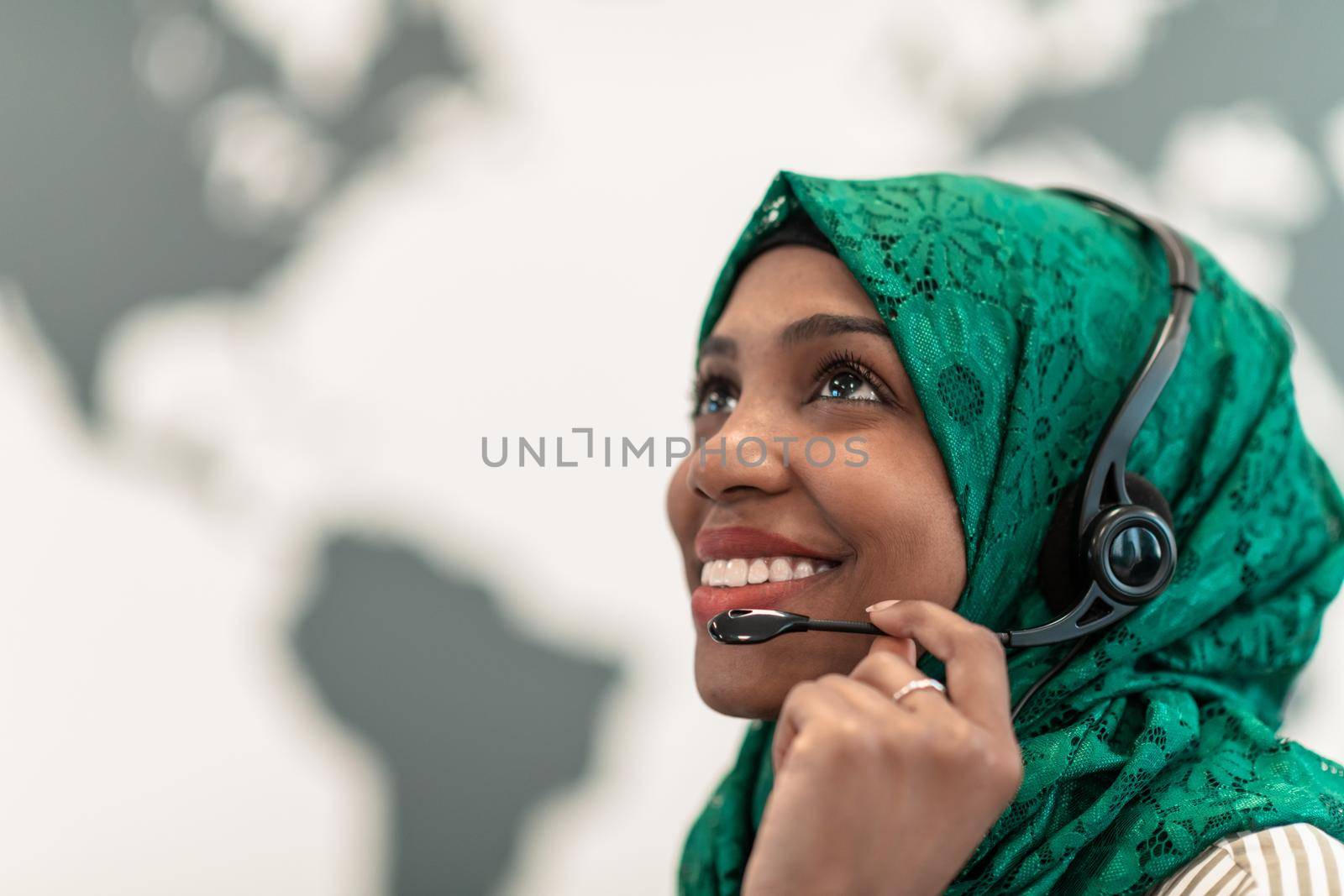 Afro Muslim female with green hijab scarf customer representative business woman with phone headset helping and supporting online with customer in modern call centre by dotshock