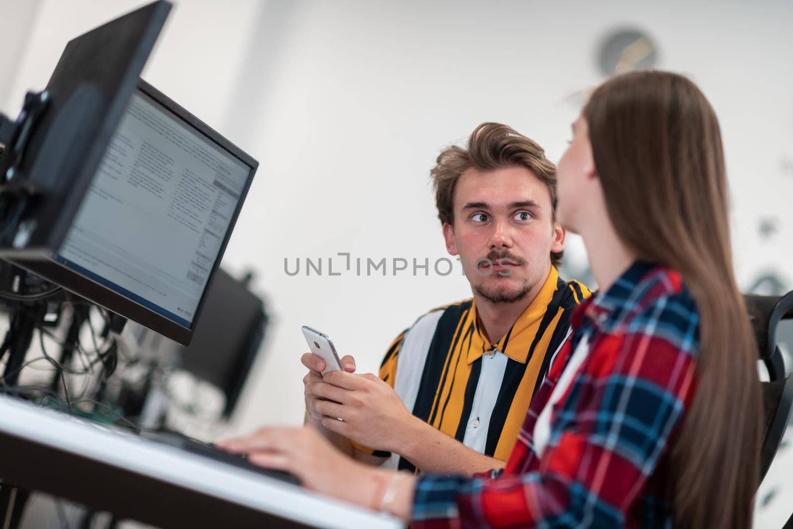 Business couple working together on a project using tablet and desktop computer at modern open plan startup office. Selective focus. High-quality photo