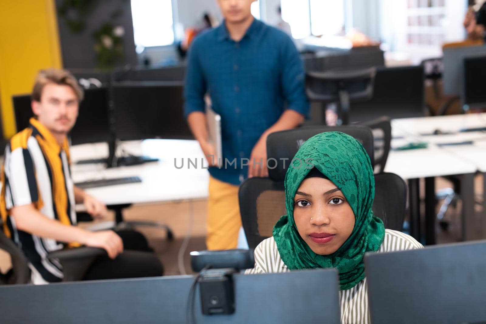 Multiethnic startup business team Arabian woman wearing a hijab on meeting in modern open plan office interior brainstorming, working on laptop and desktop computer. Selective focus by dotshock